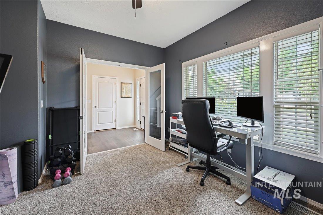 Carpeted home office featuring french doors and a ceiling fan