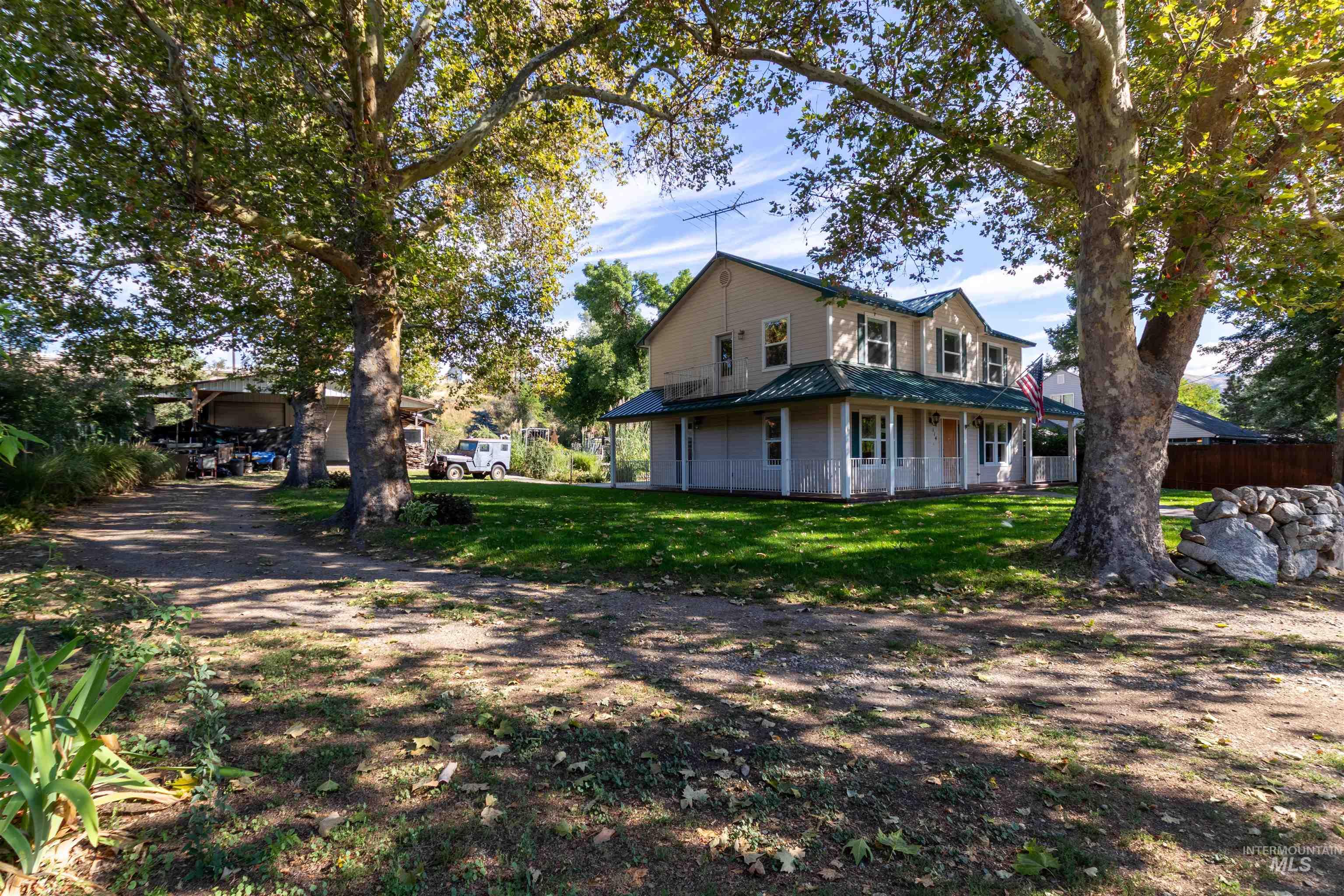 View of front facade featuring, side yard, mature landscaping, driveway to shop
