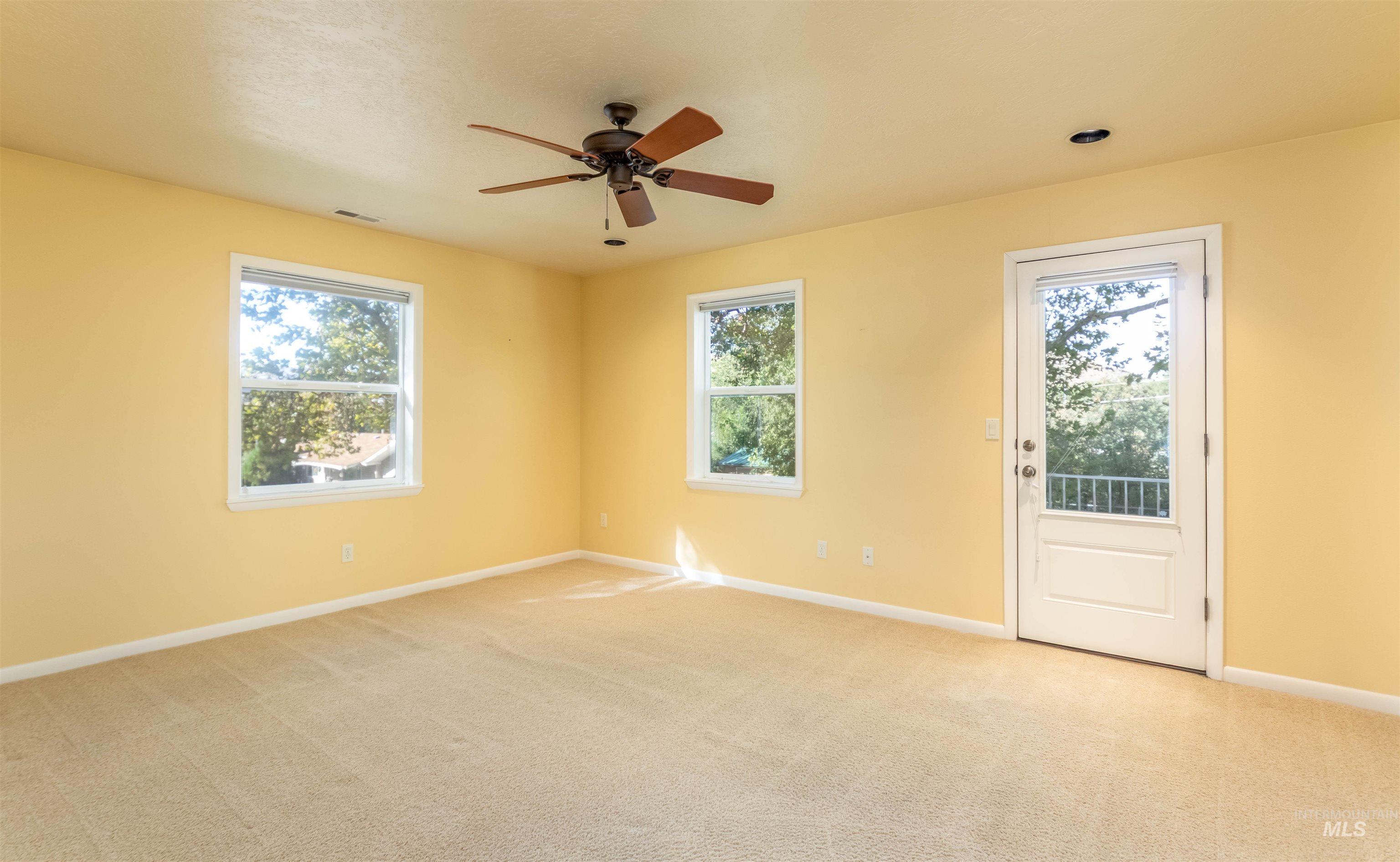 Carpeted master bedroom featuring healthy amount of natural light and a ceiling fan