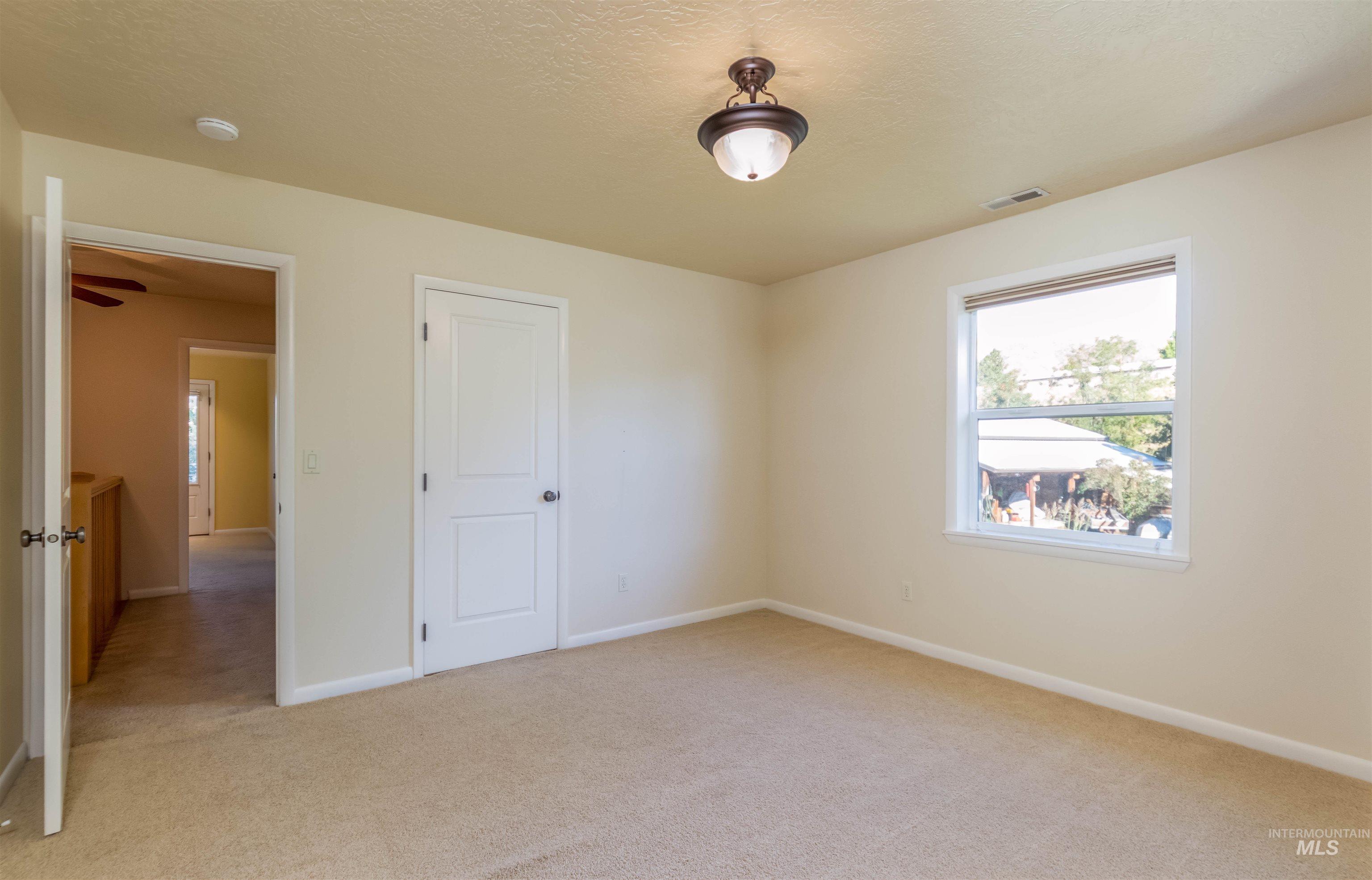 bedroom with featuring light carpet, a textured ceiling, access to master bathroom and NO closet