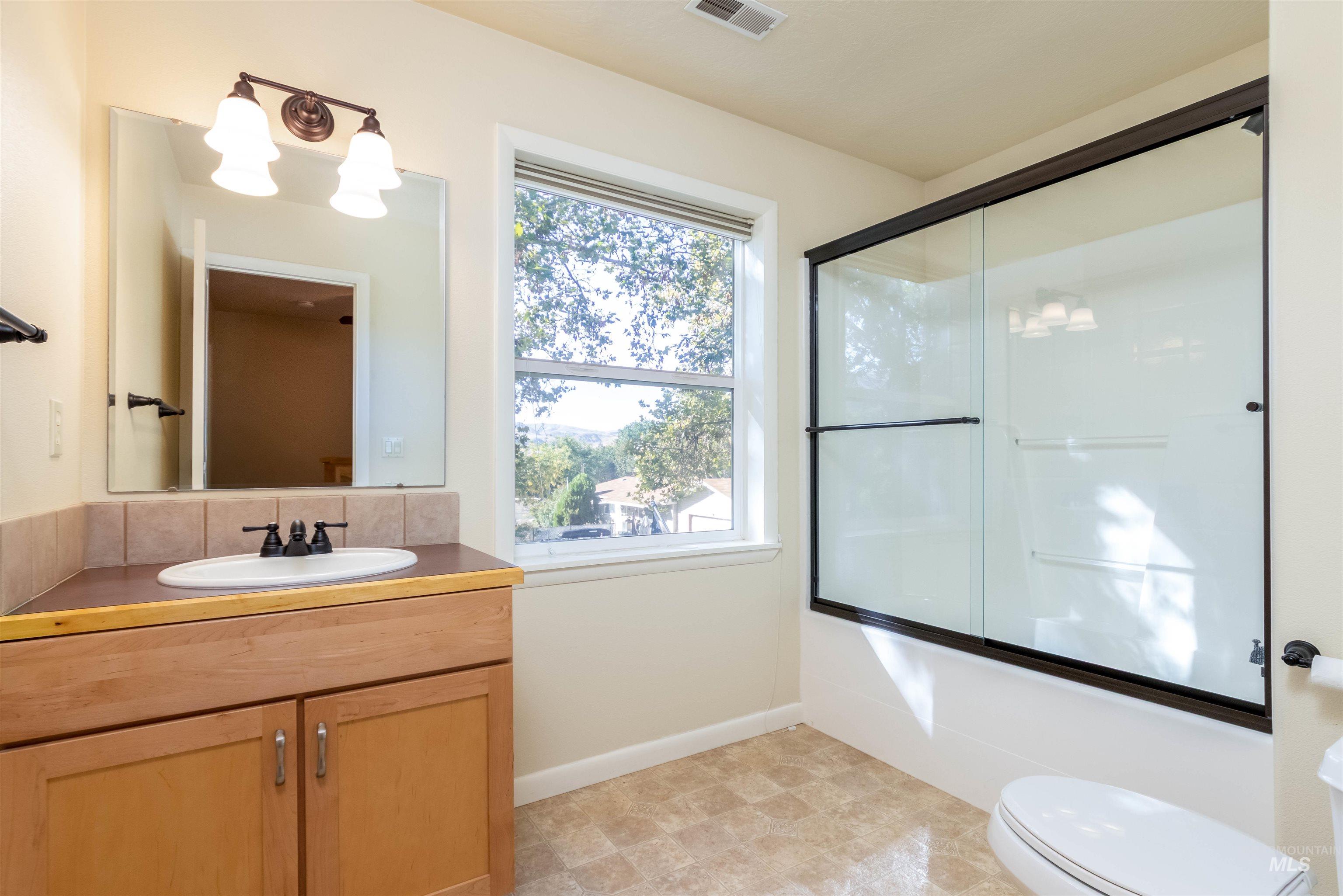 Bathroom with vanity, combined bath / shower with glass door, and a chandelier