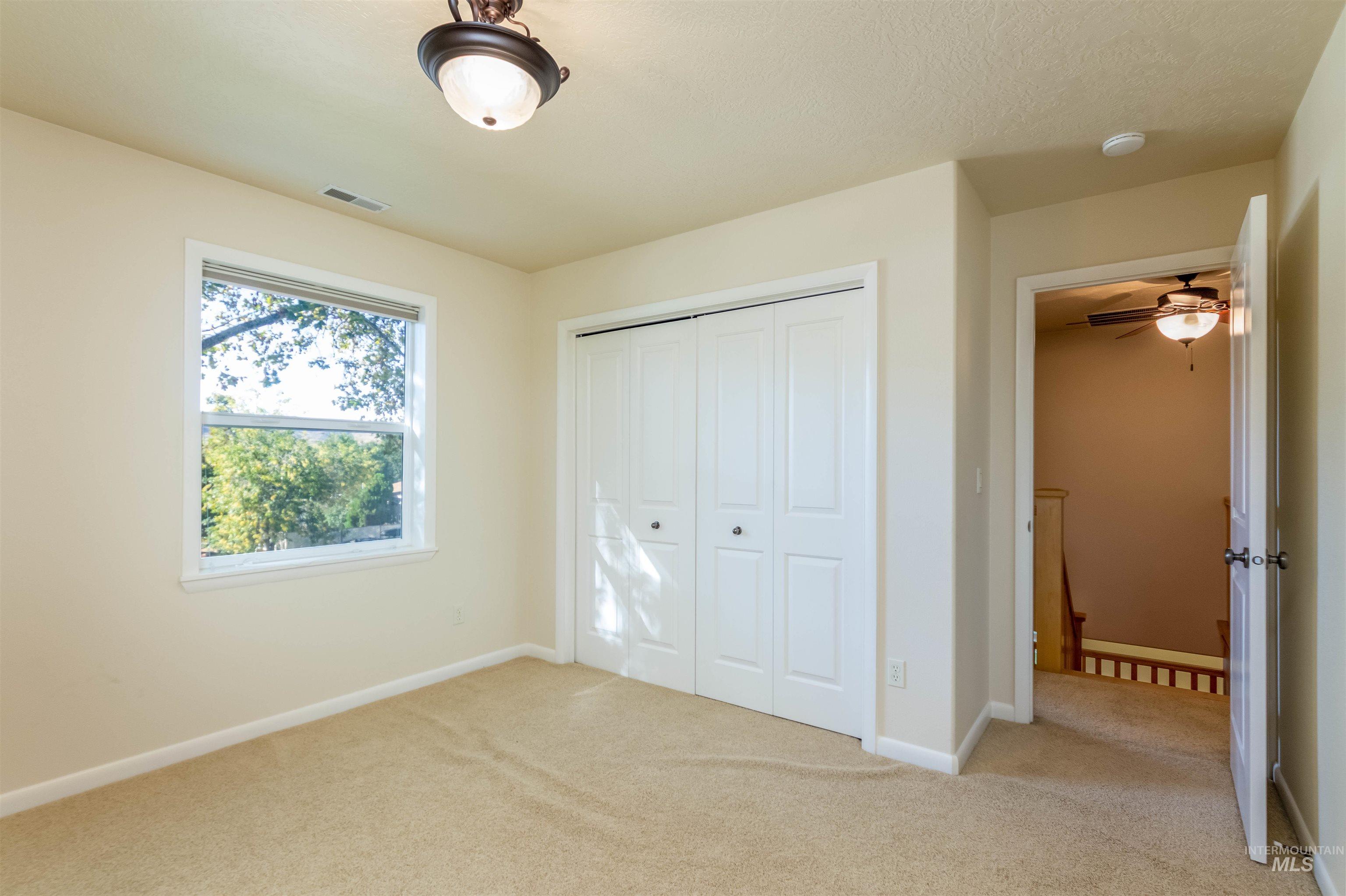 Bedroom with light colored carpet and a closet
