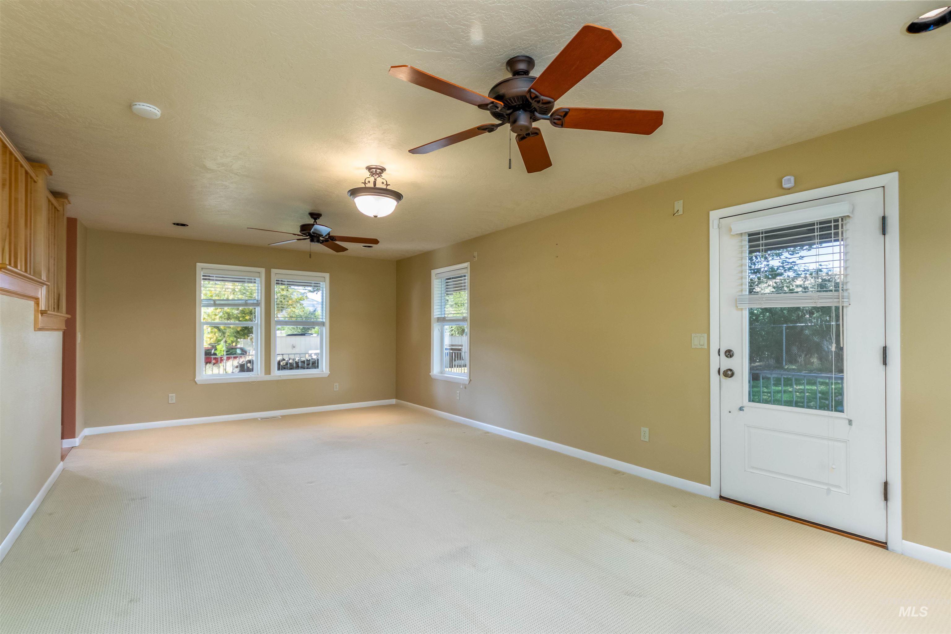 Living room with light carpet, a ceiling fan, and exterior door to the side porch