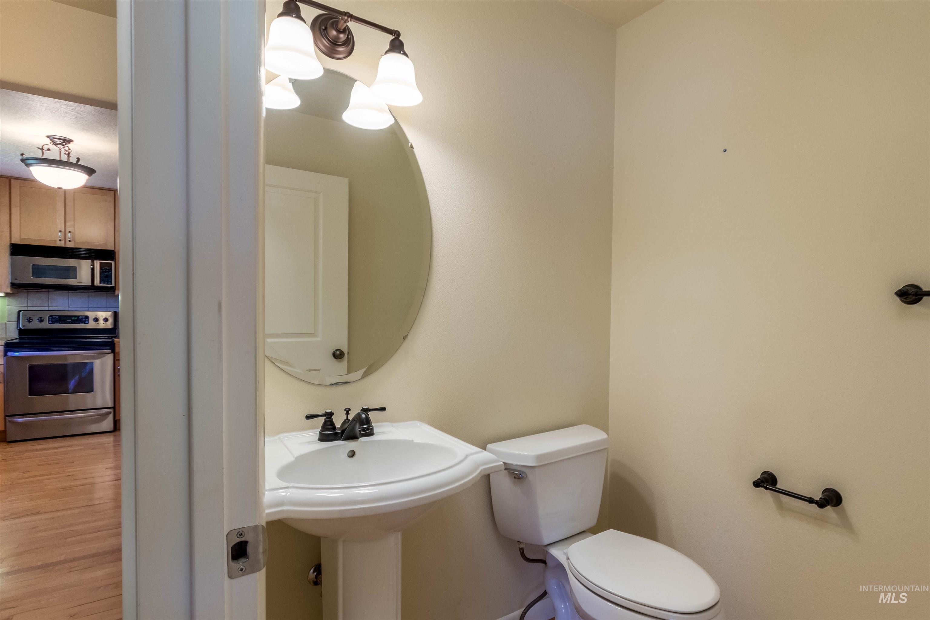 Guest half bath featuring backsplash, a chandelier, and wood finished floors