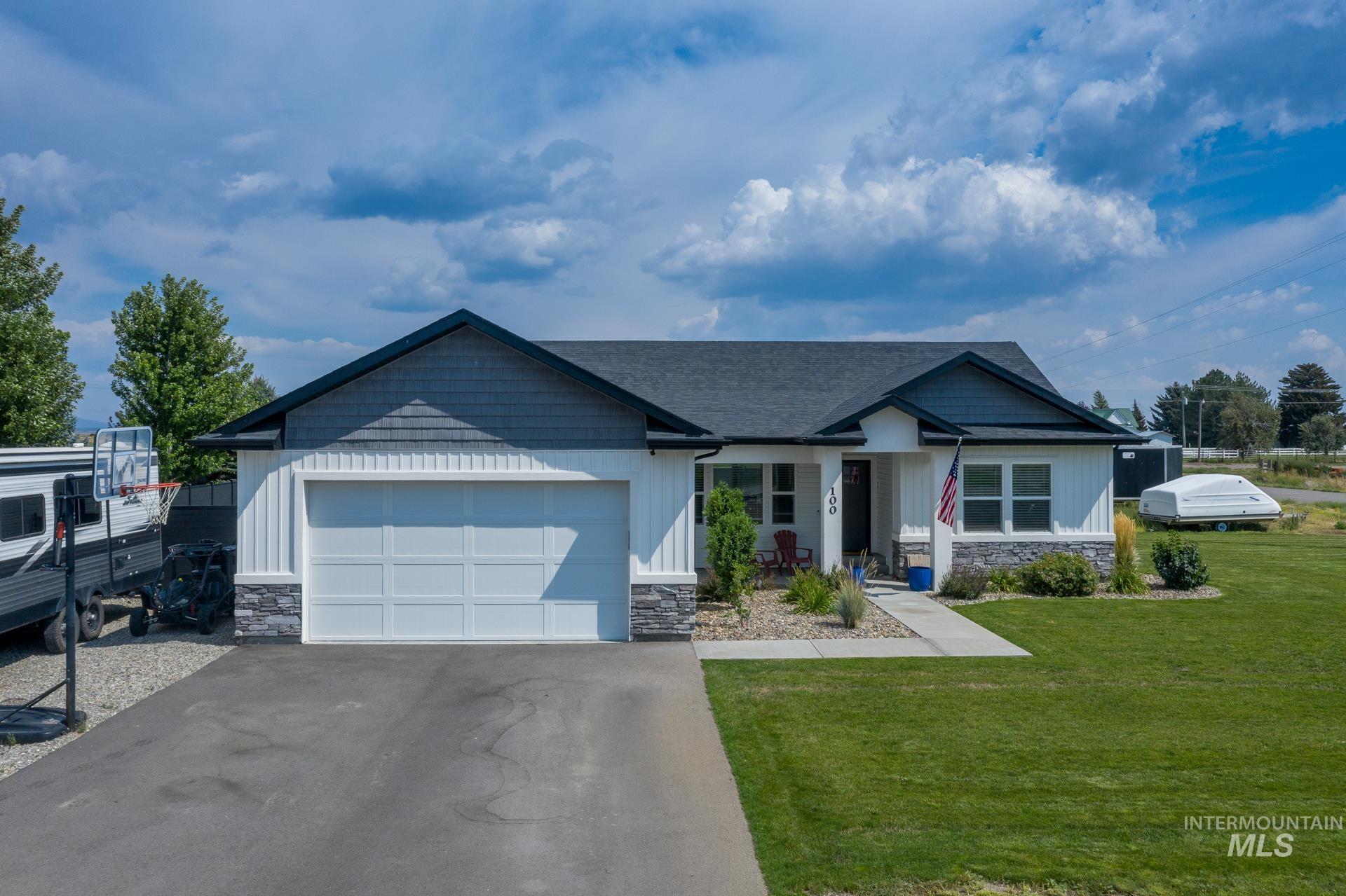Craftsman-style home featuring stone siding, asphalt driveway, a front yard, and board and batten siding