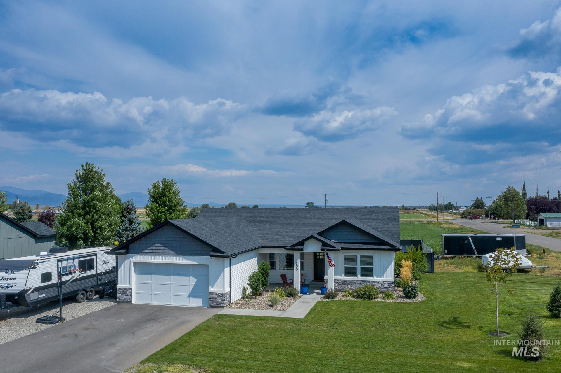 View of front of house with stone siding, driveway, a garage, and a front yard