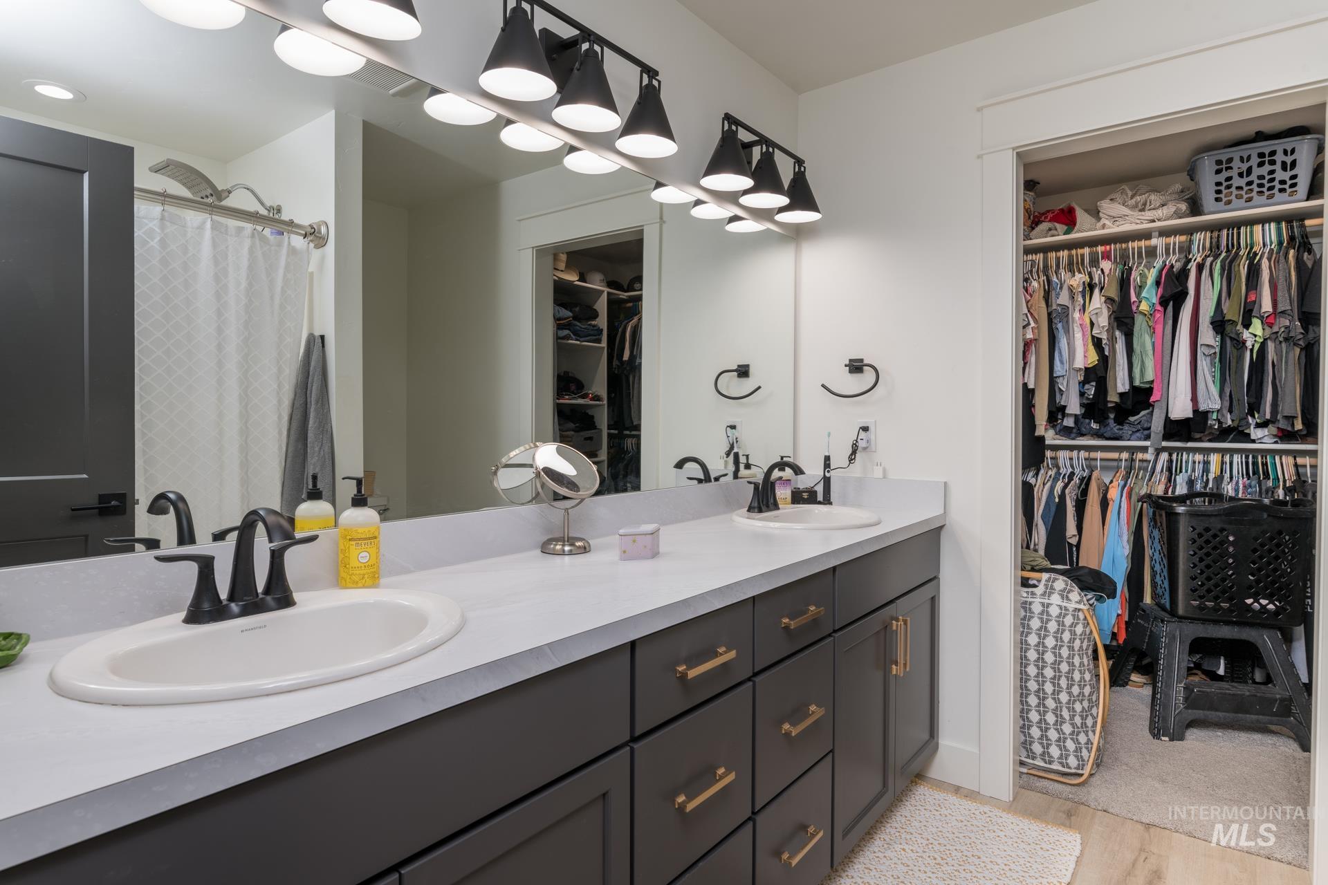 Bathroom with a walk in closet, double vanity, light wood-style floors, and a shower with shower curtain