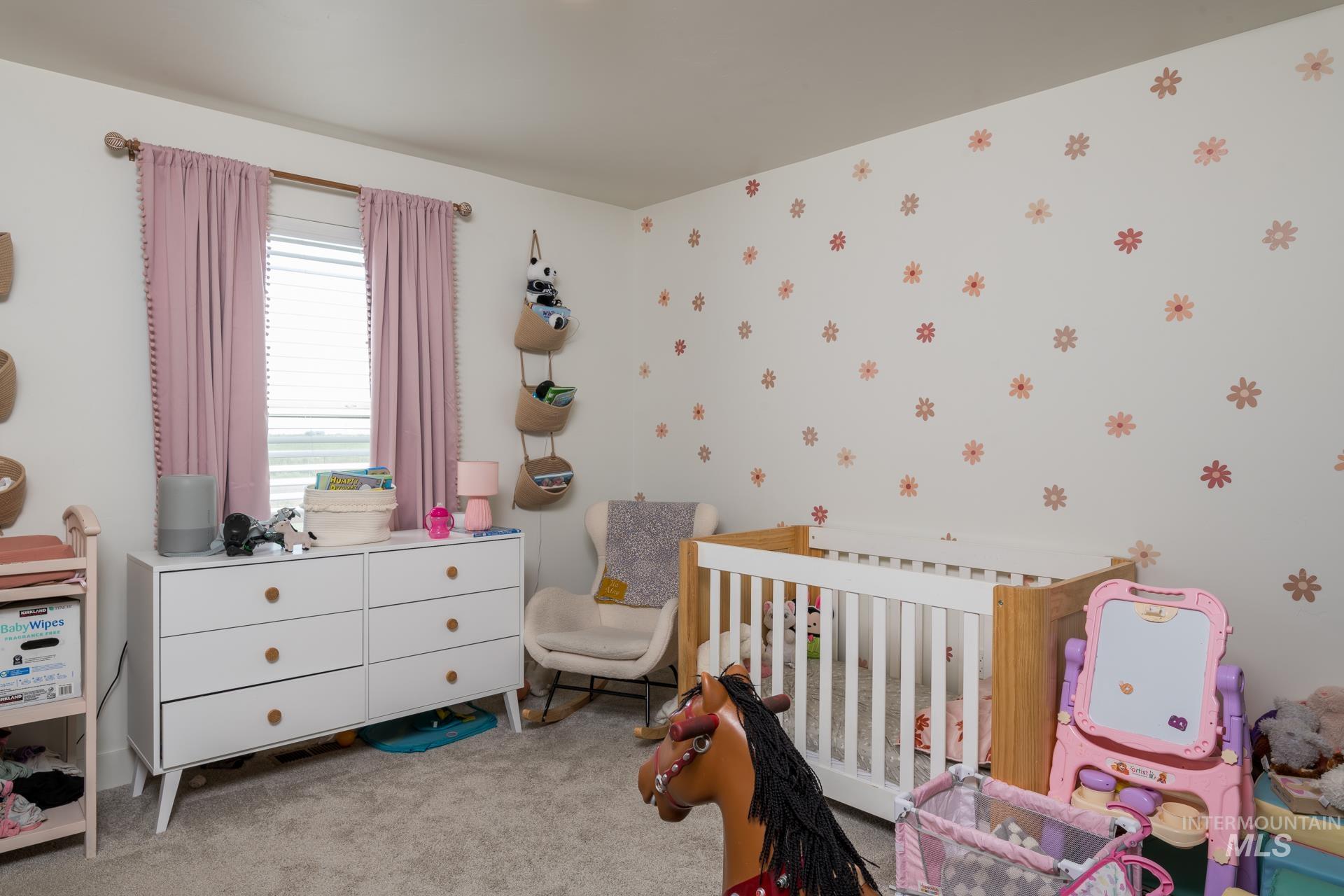 Bedroom featuring light carpet and a crib