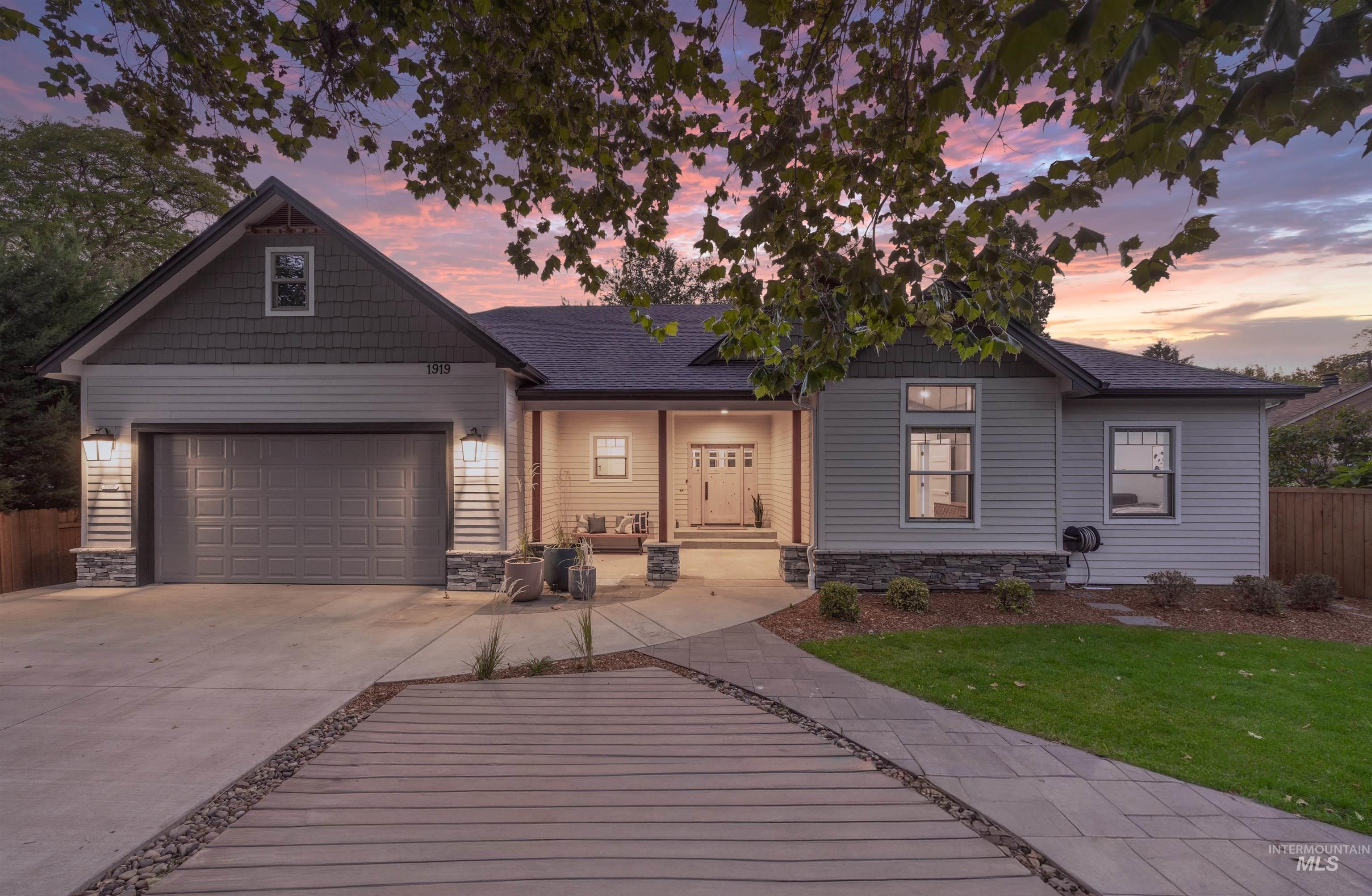 View of front facade featuring a porch, stone siding, driveway, a garage, and roof with shingles