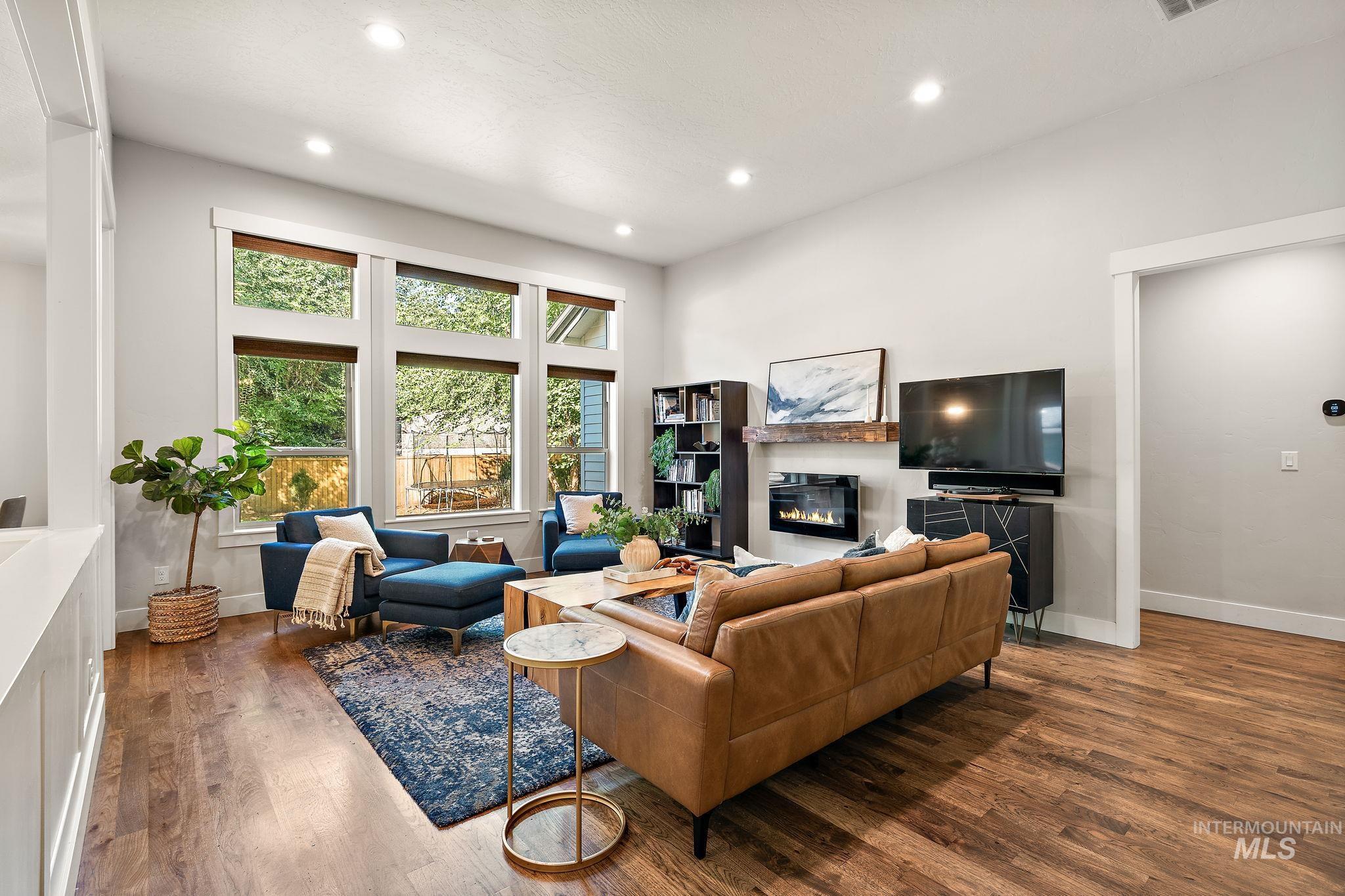 Living area with a glass covered fireplace, recessed lighting, and wood finished floors