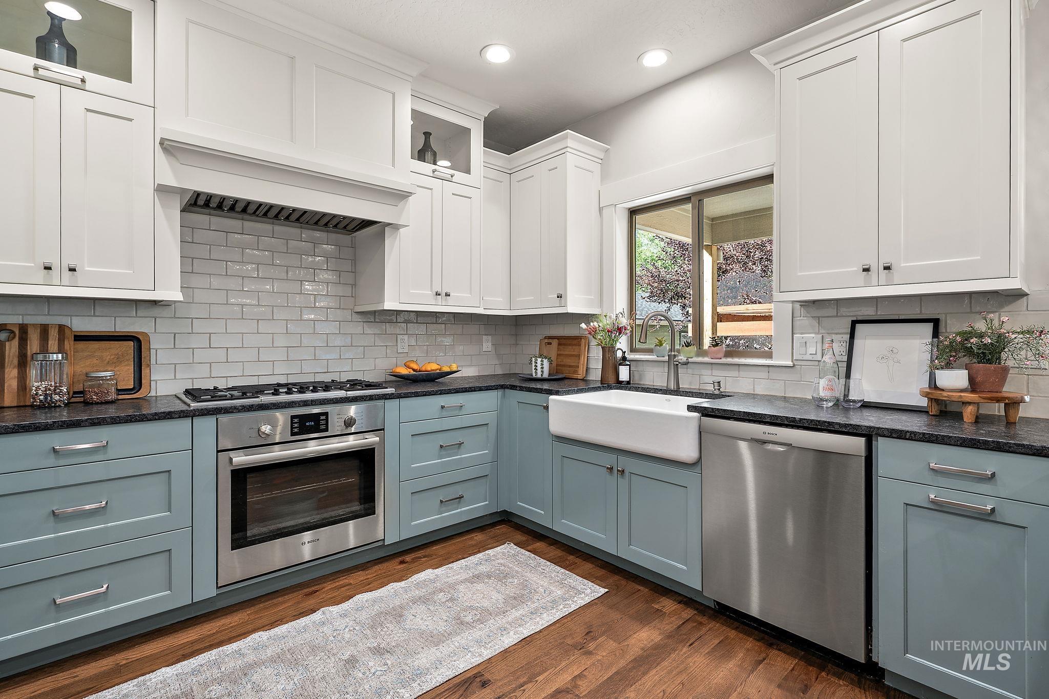 Kitchen with white cabinets, stainless steel appliances, glass insert cabinets, dark wood-style flooring, and recessed lighting