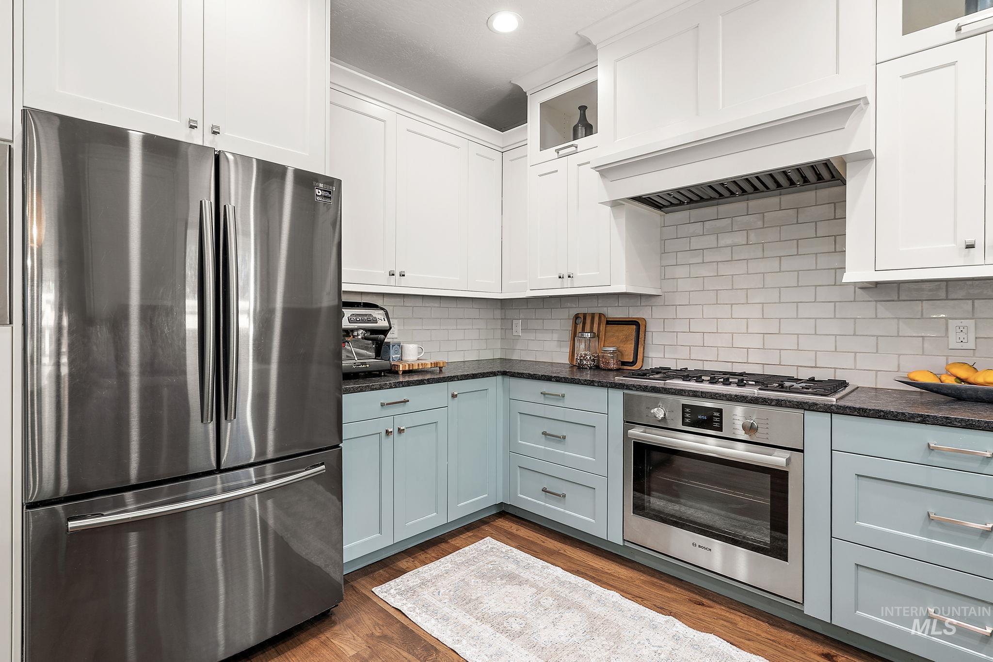 Kitchen featuring stainless steel appliances, white cabinetry, dark wood-style floors, dark stone countertops, and recessed lighting