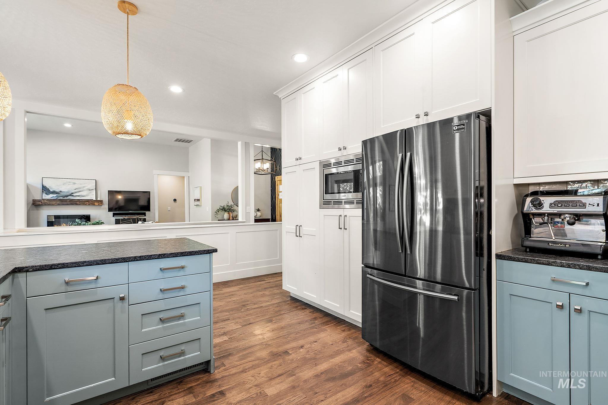 Kitchen with stainless steel appliances, dark wood-style floors, white cabinetry, pendant lighting, and recessed lighting