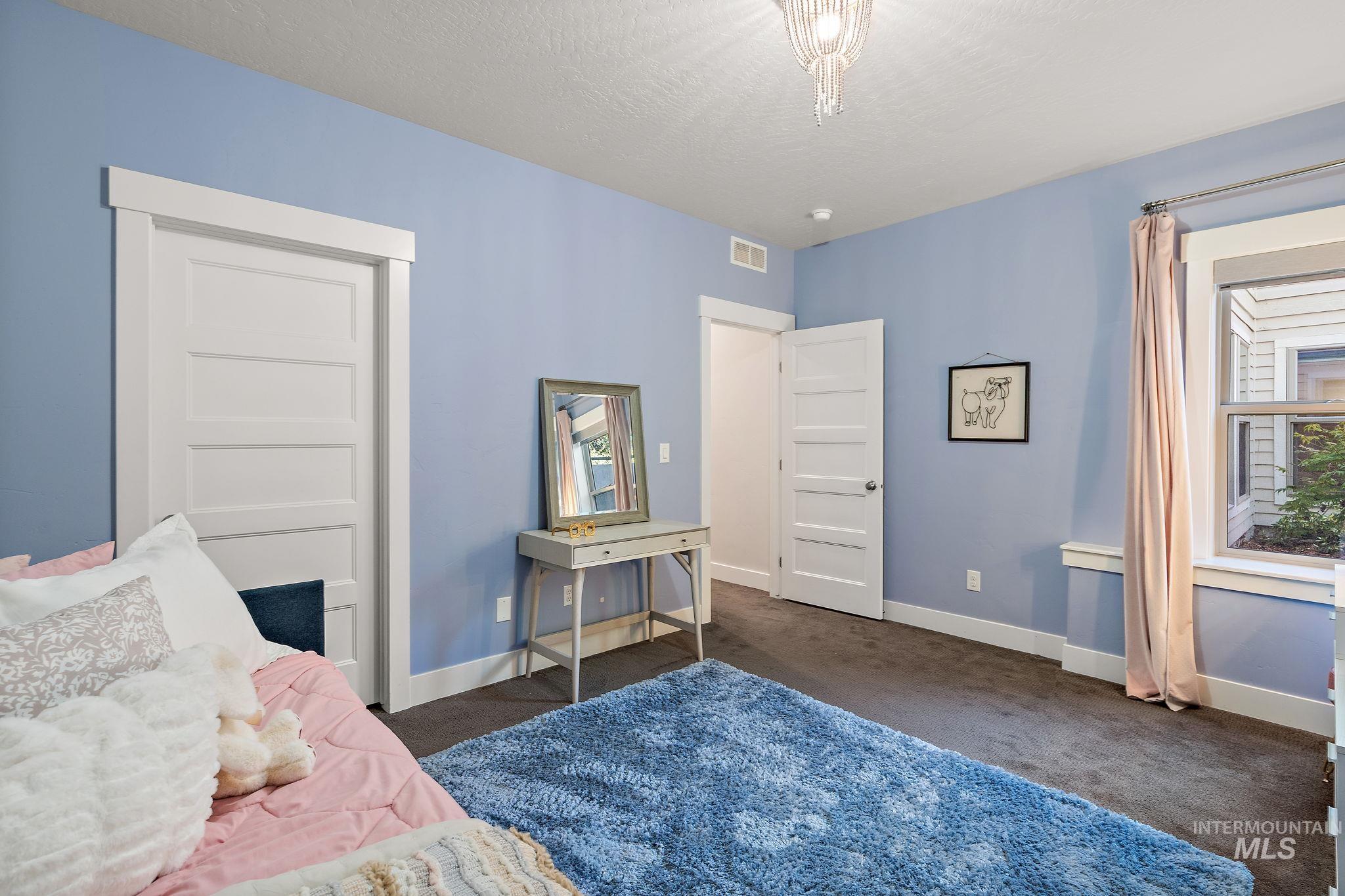 Bedroom with dark colored carpet and a textured ceiling