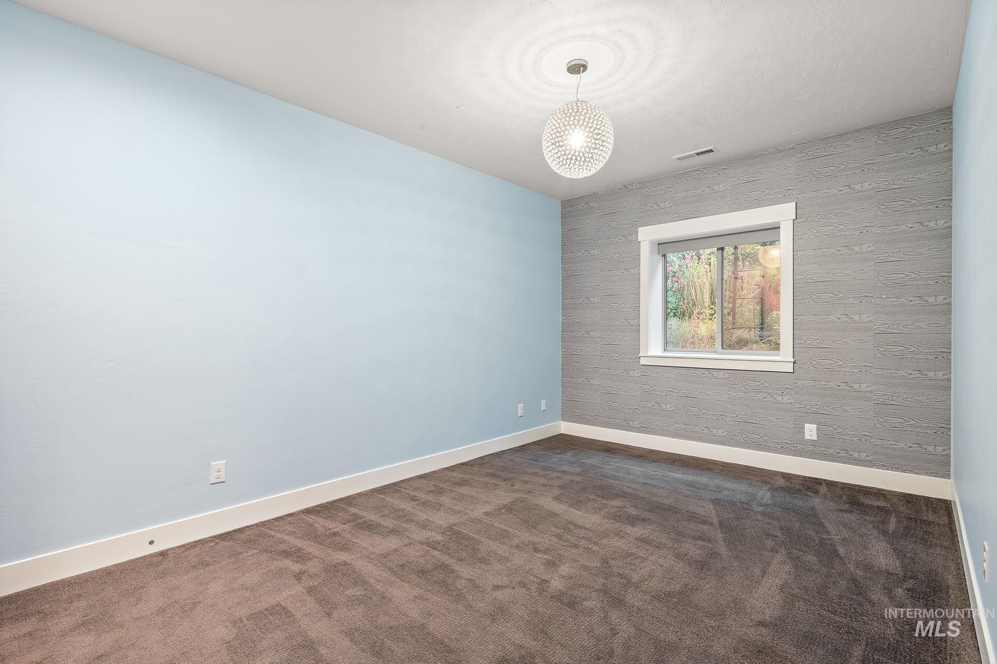 Unfurnished room with dark colored carpet and a chandelier