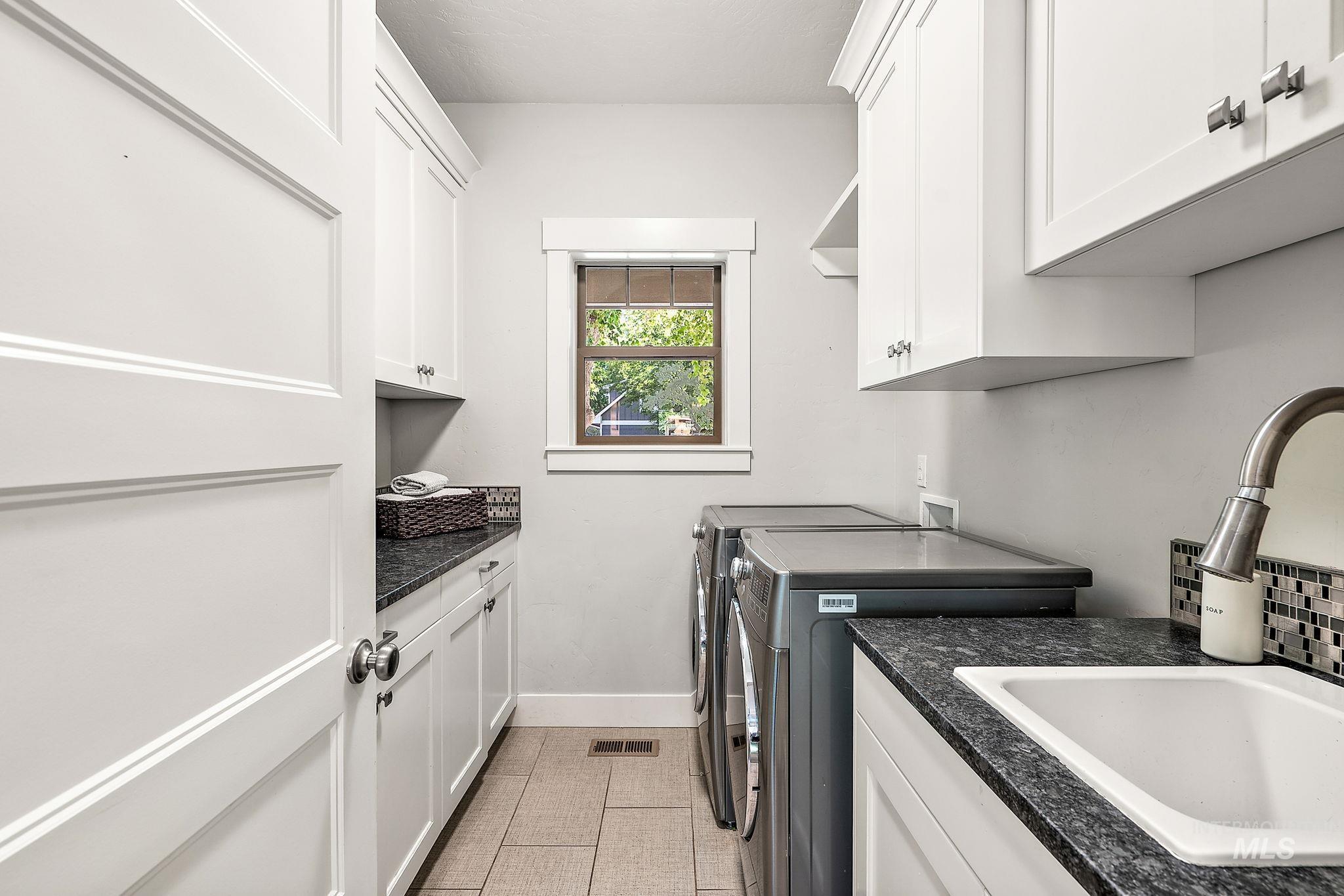 Laundry area with washer and dryer, light tile patterned flooring, and cabinet space