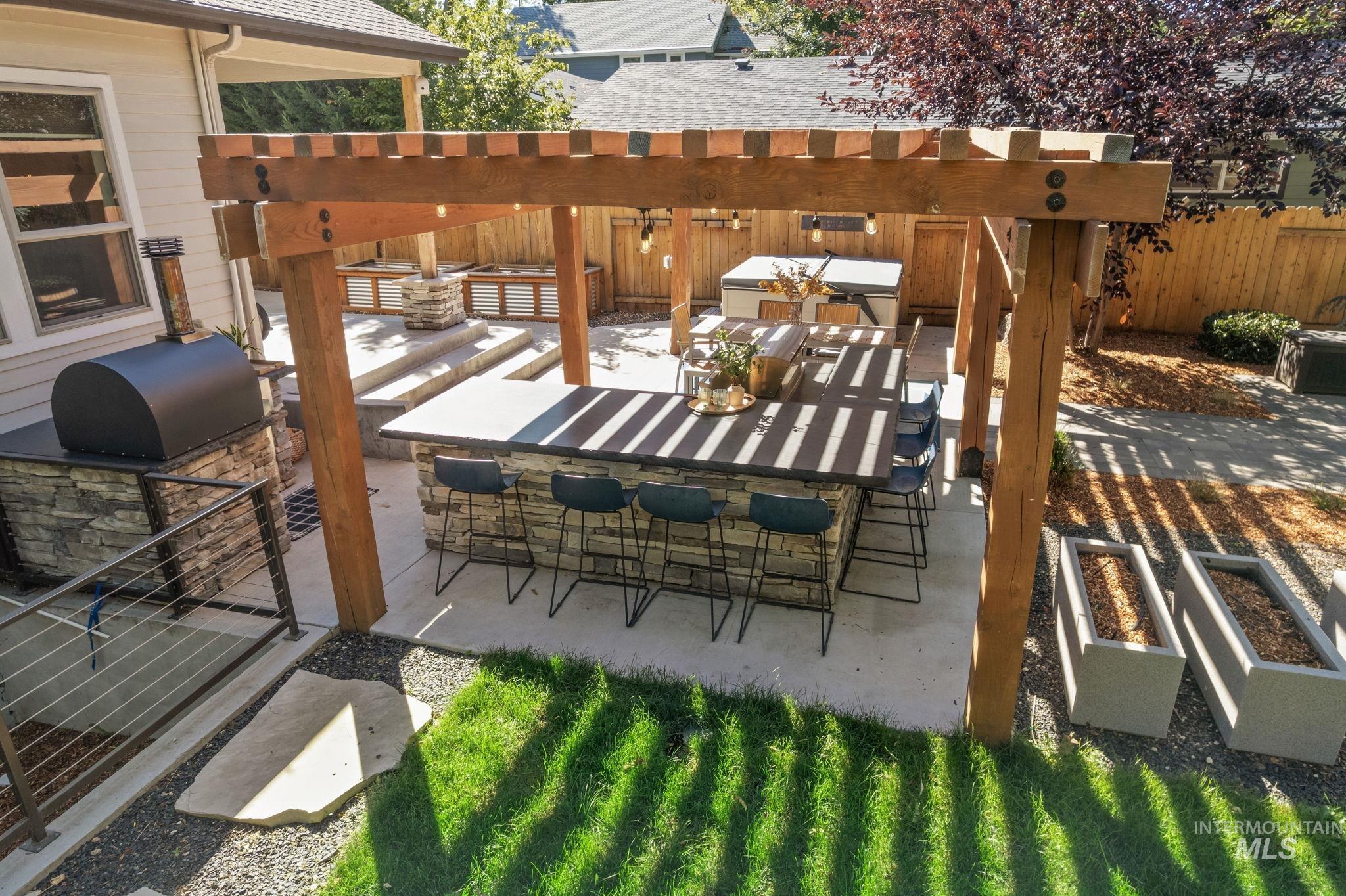 View of patio featuring a garden, a pergola, and an outdoor kitchen