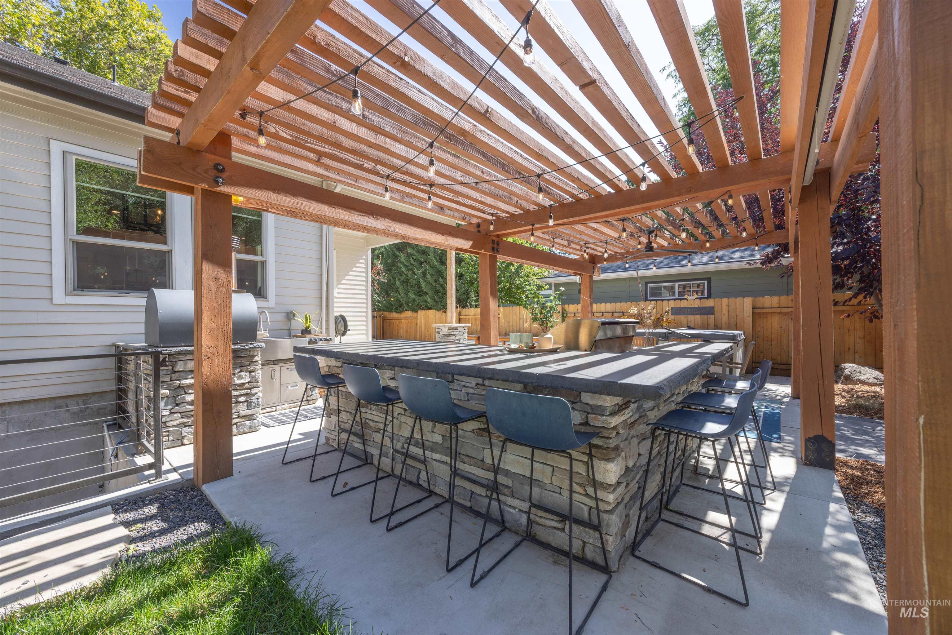 View of patio with area for grilling and a pergola