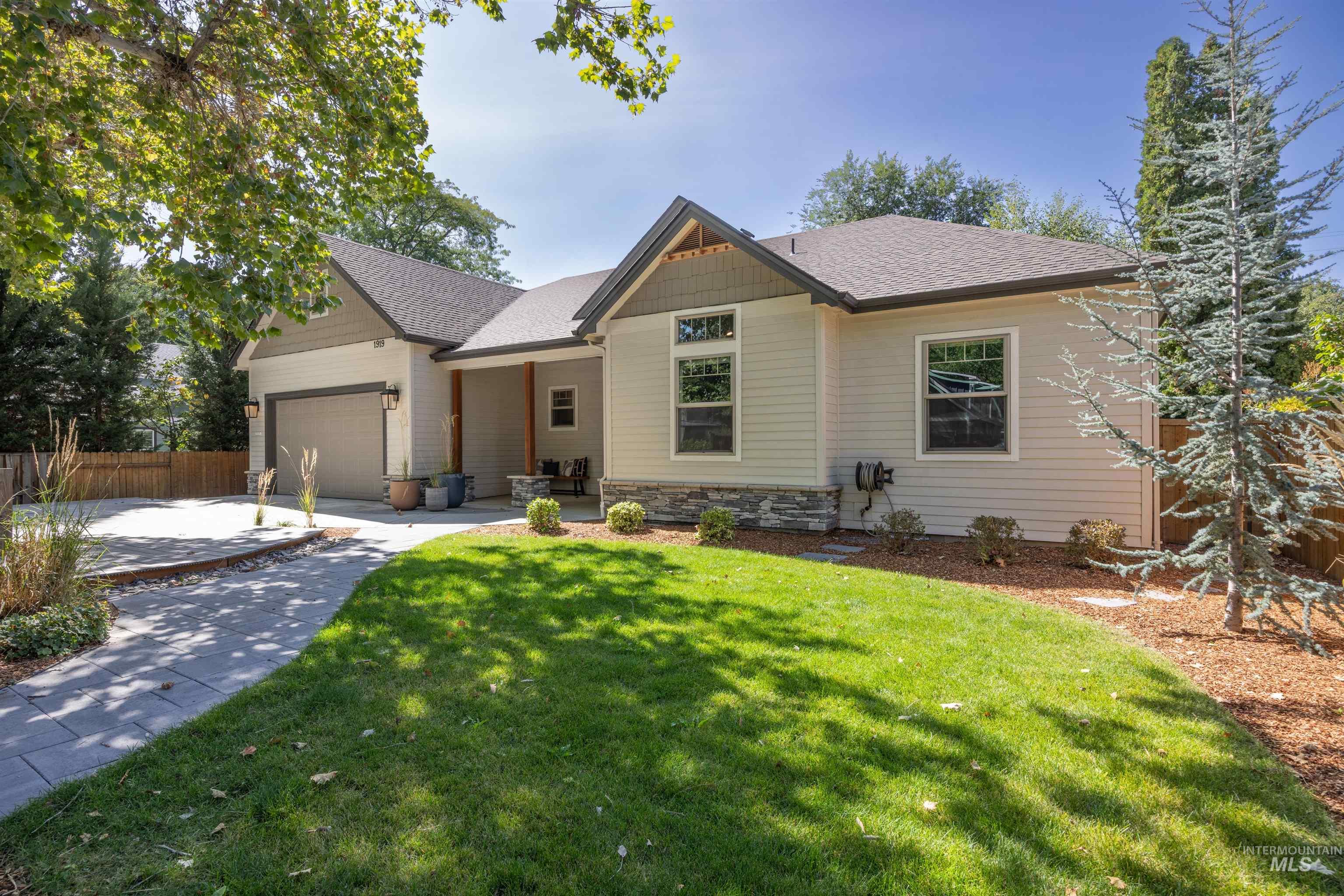 View of front facade with an attached garage, stone siding, a shingled roof, and concrete driveway