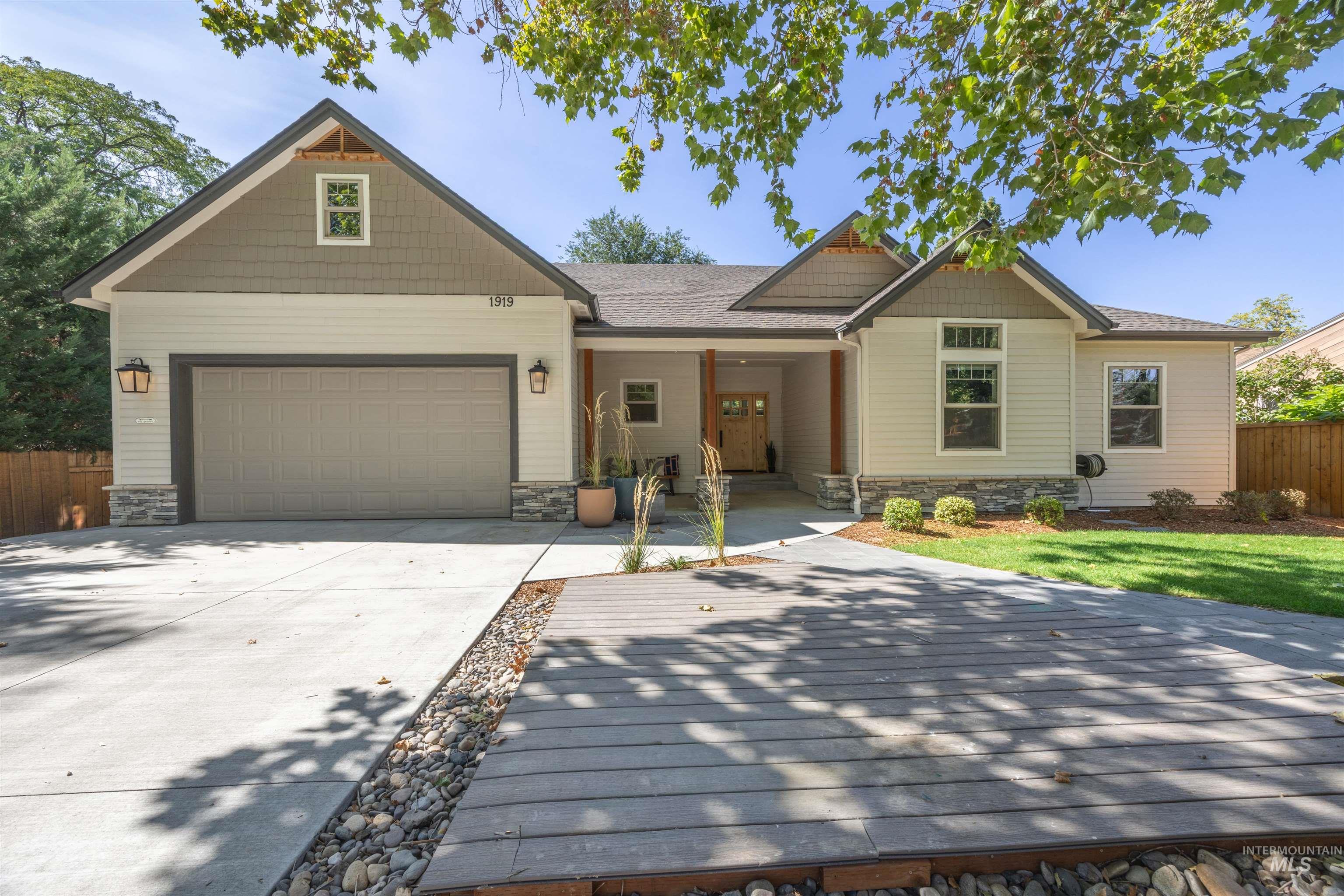 Craftsman inspired home featuring stone siding, a porch, driveway, and a garage