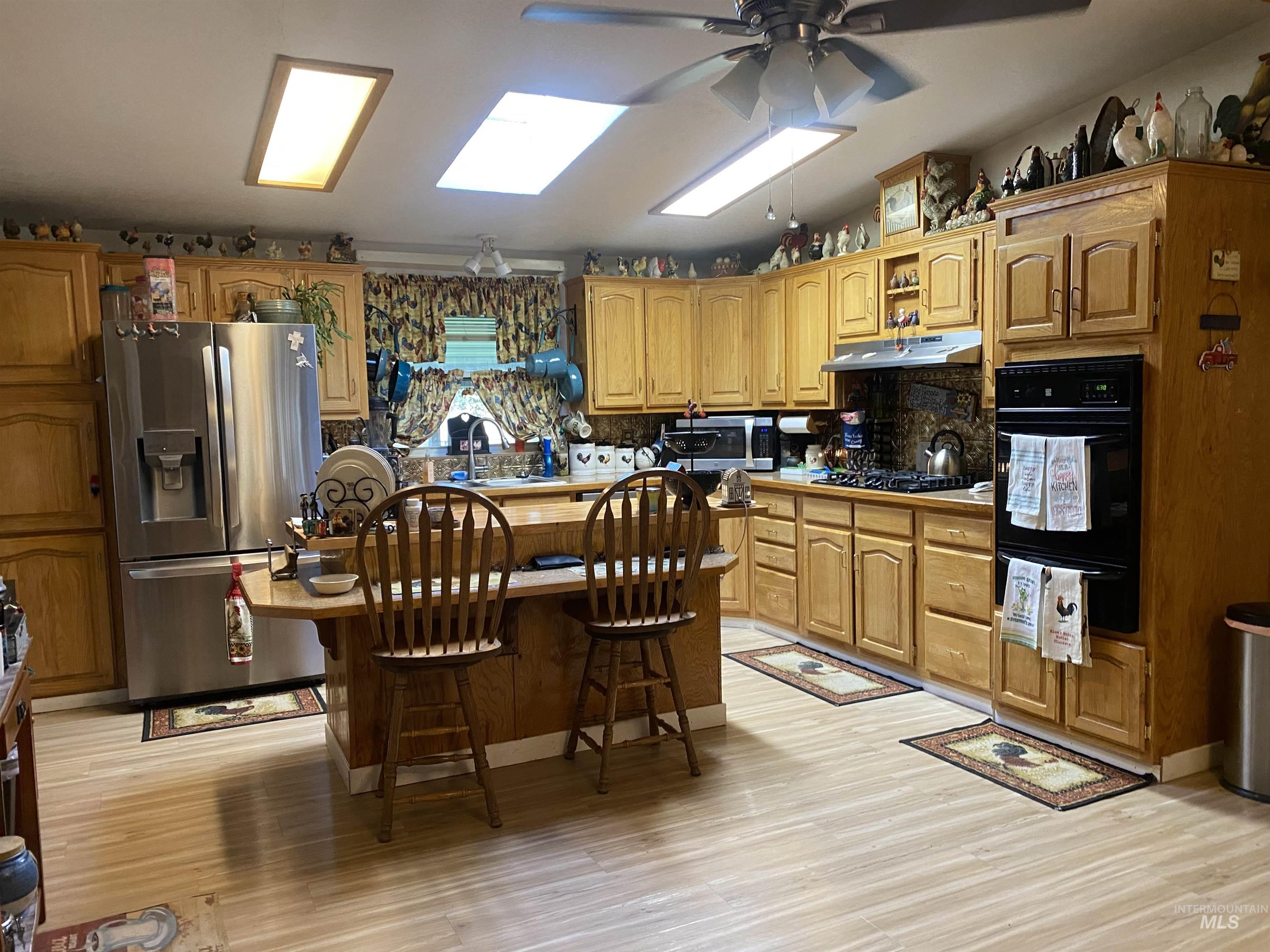 Kitchen with stainless steel appliances, tasteful backsplash, a warming drawer, a center island, and a kitchen bar