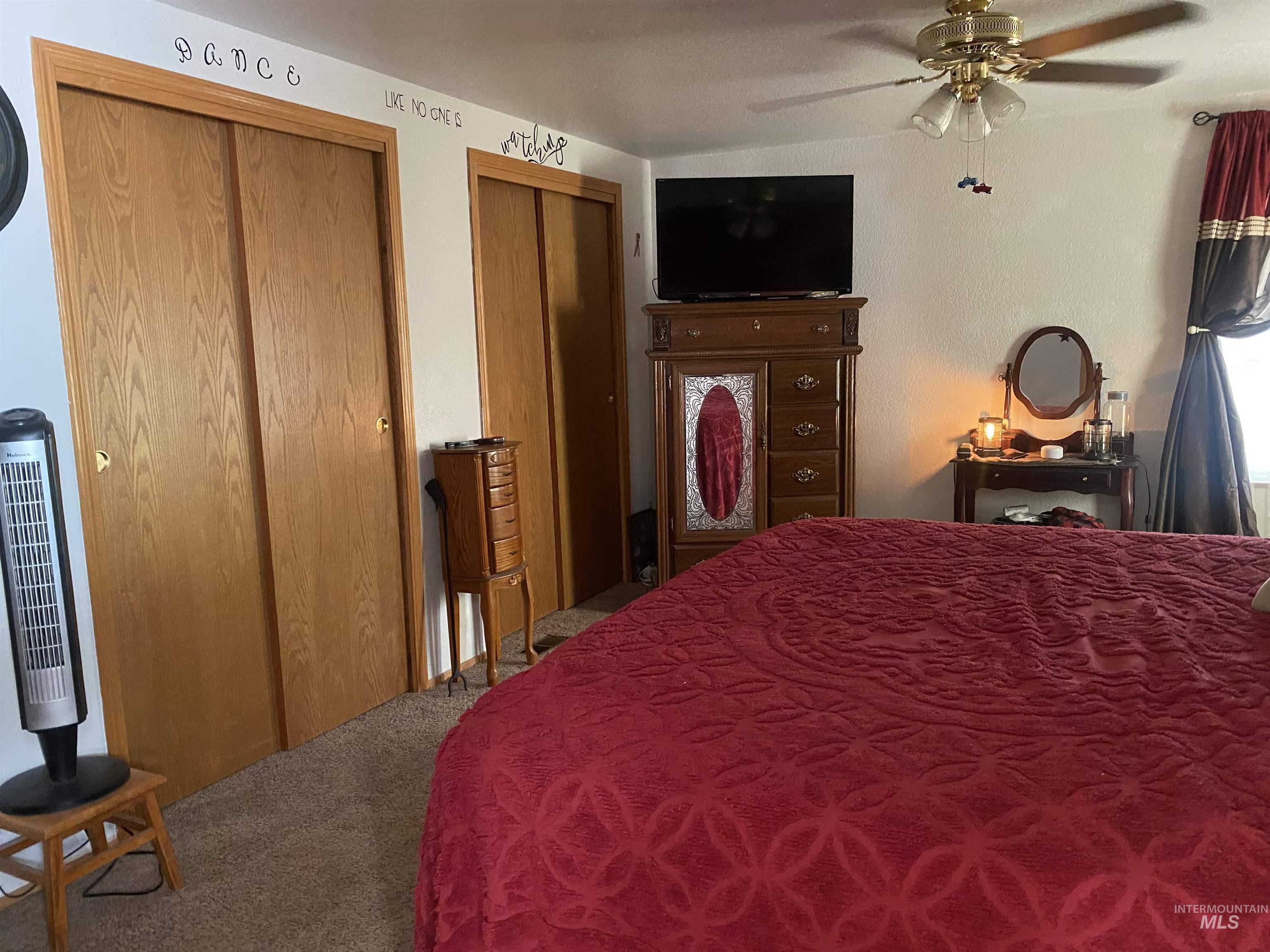 Bedroom featuring multiple closets, ceiling fan, carpet floors, and heating unit