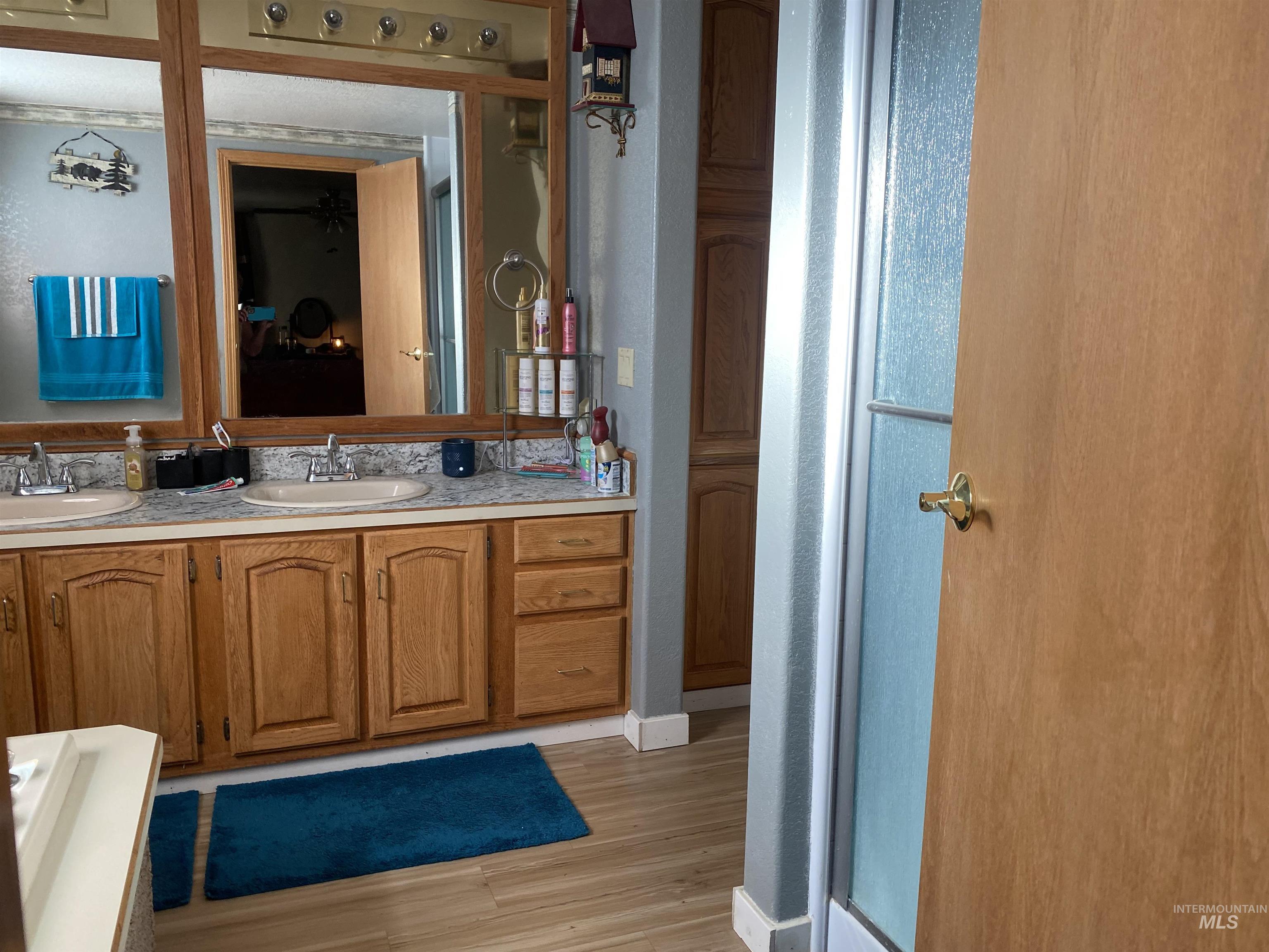 Full bath with double vanity and light wood-style flooring