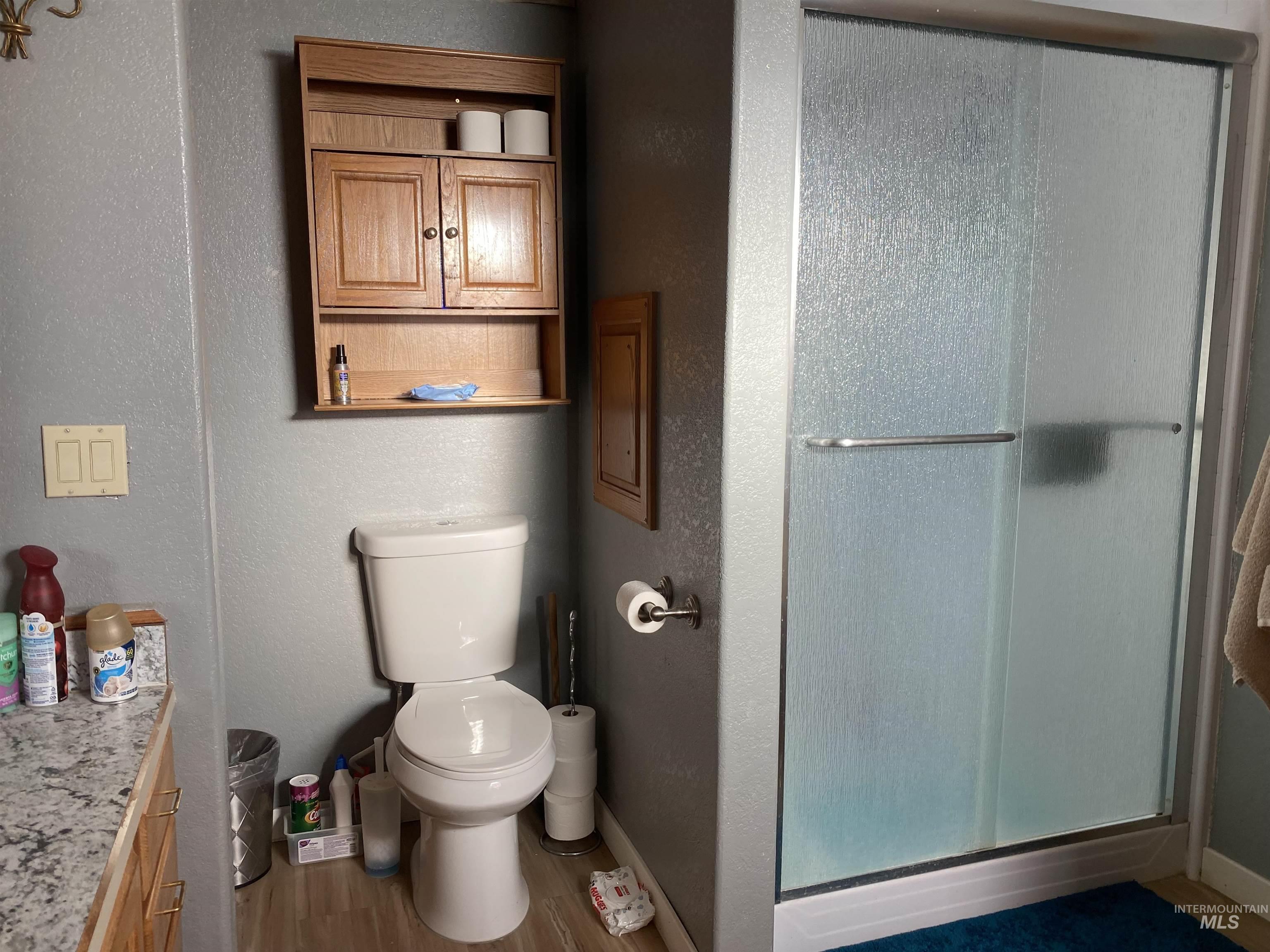 Bathroom with vanity, a shower stall, wood finished floors, and a textured wall