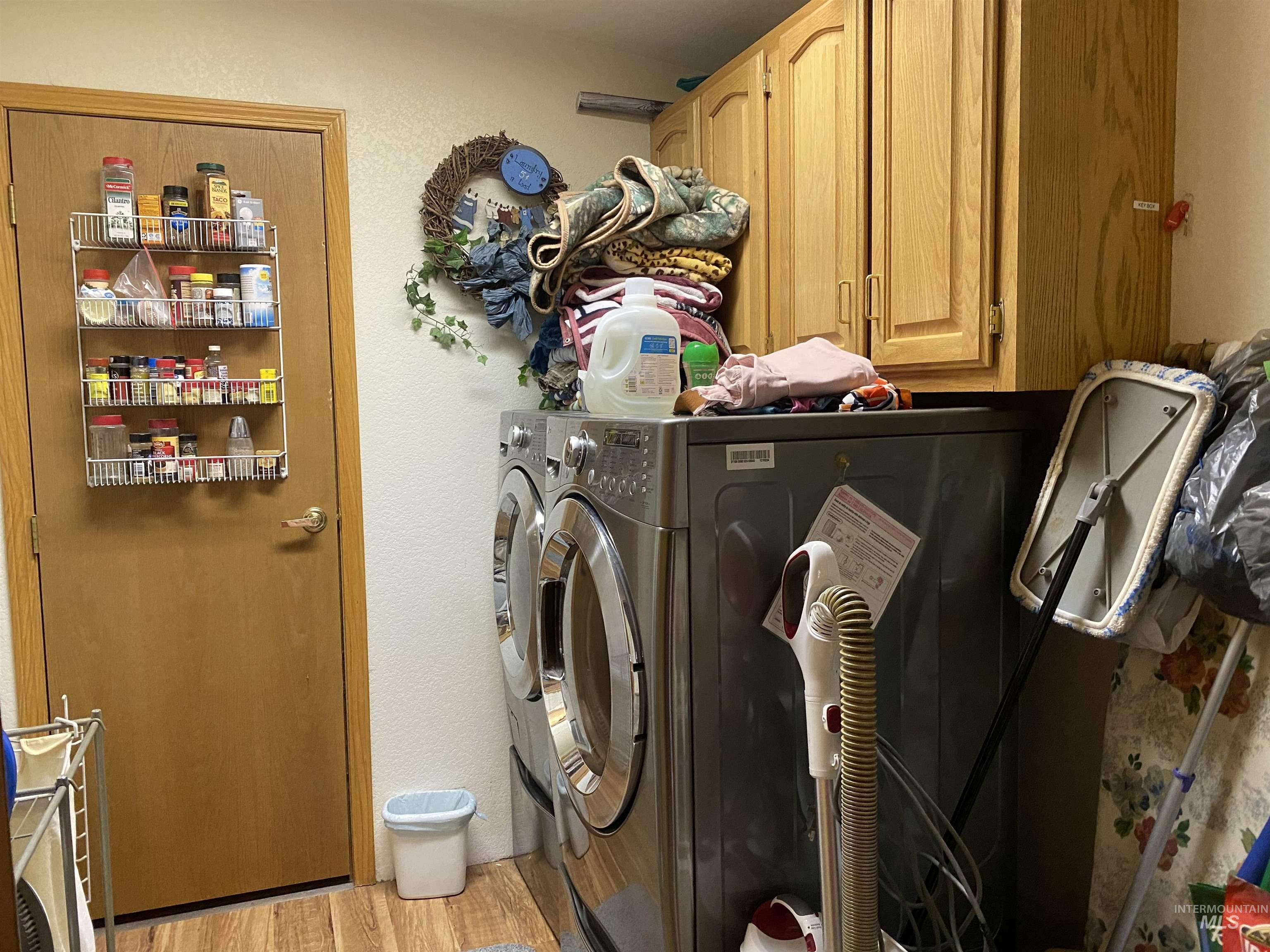 Laundry room with light wood finished floors, washing machine and dryer, and cabinet space