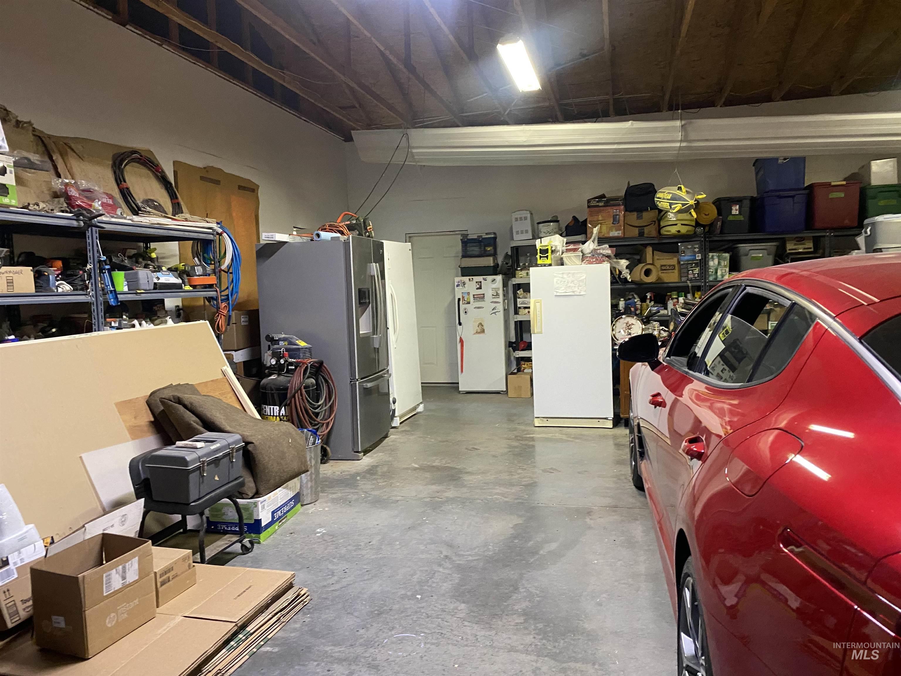 Garage featuring stainless steel fridge with ice dispenser and freestanding refrigerator