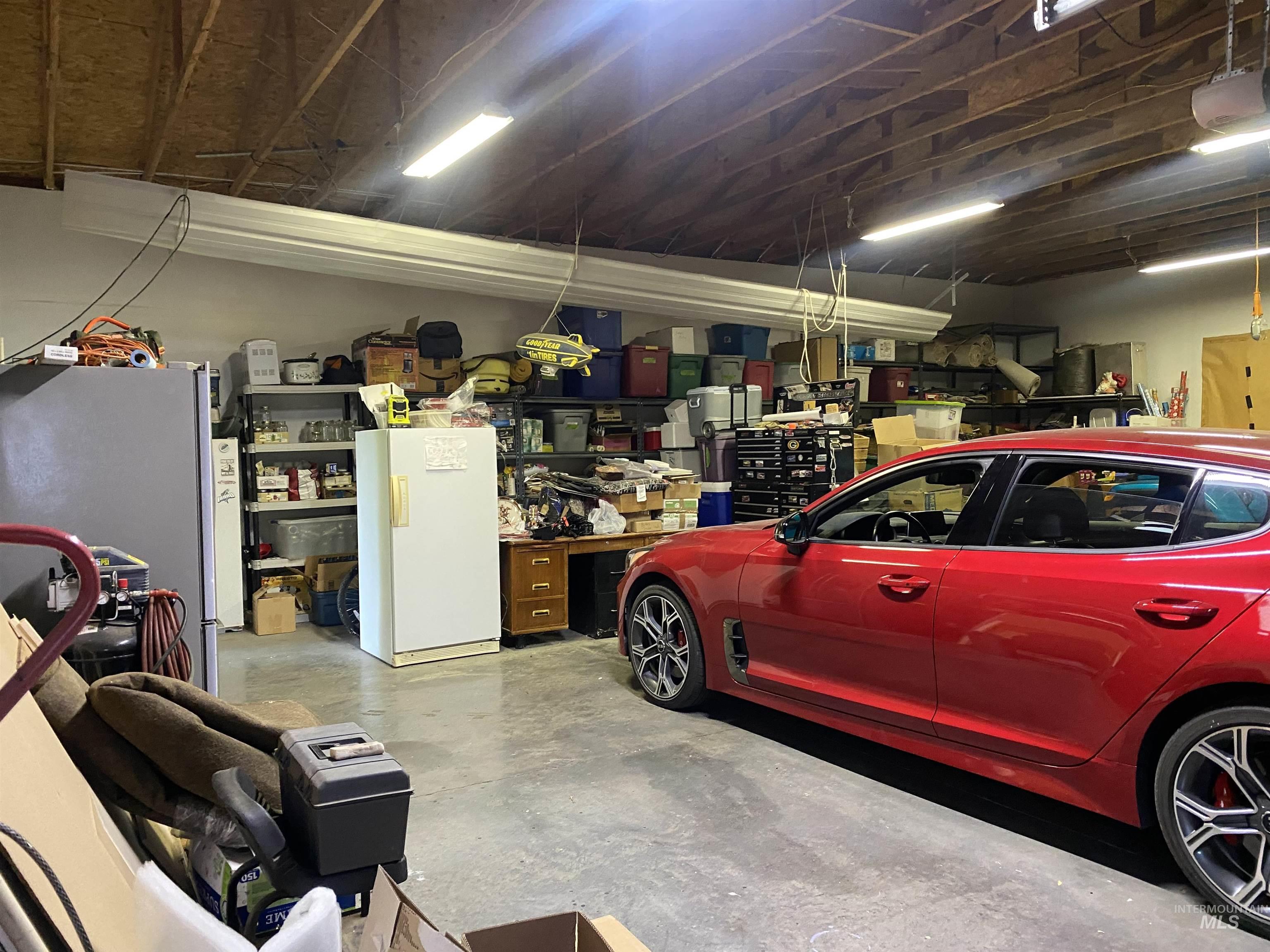 Garage featuring freestanding refrigerator, a garage door opener, and a workshop area