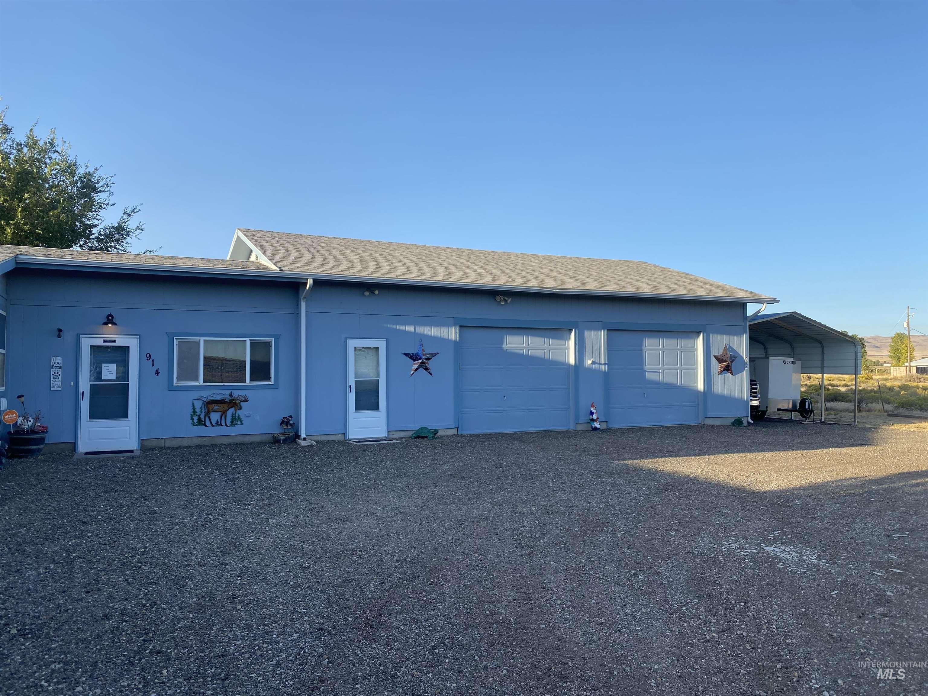 Back of house featuring roof with shingles, gravel driveway, and a carport