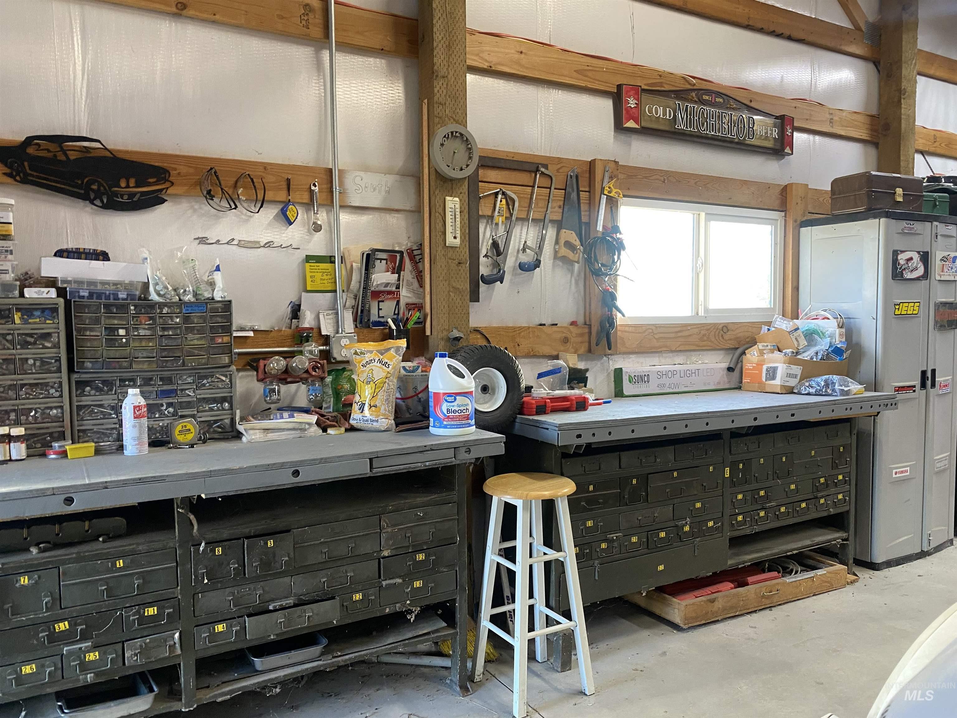 Interior space with a workshop area, unfinished concrete flooring, and freestanding refrigerator
