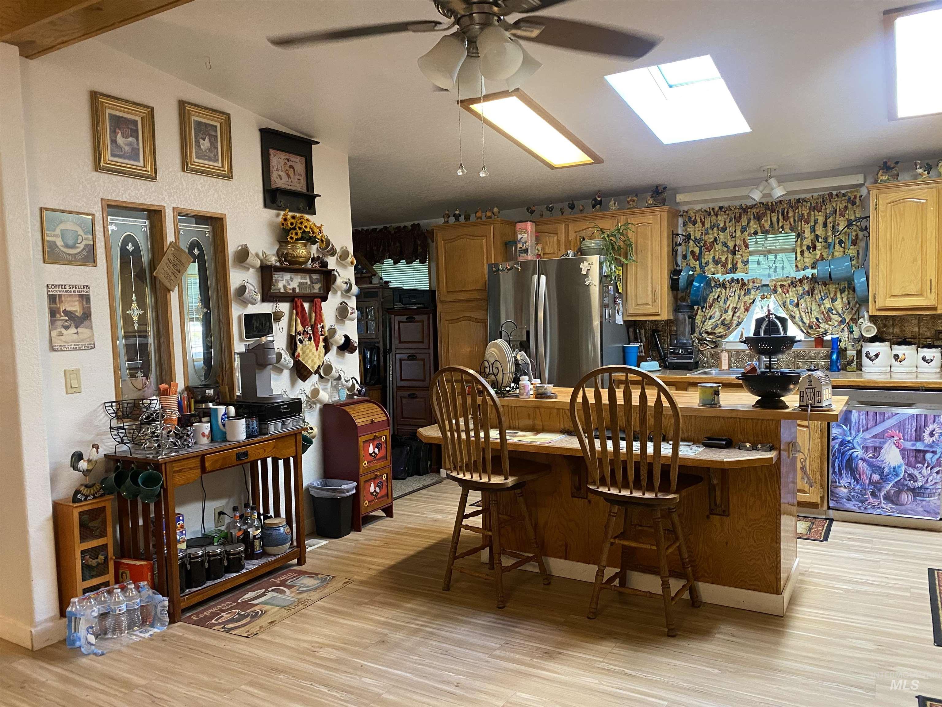 Dining room featuring light wood-style floors, ceiling fan, vaulted ceiling, and a skylight