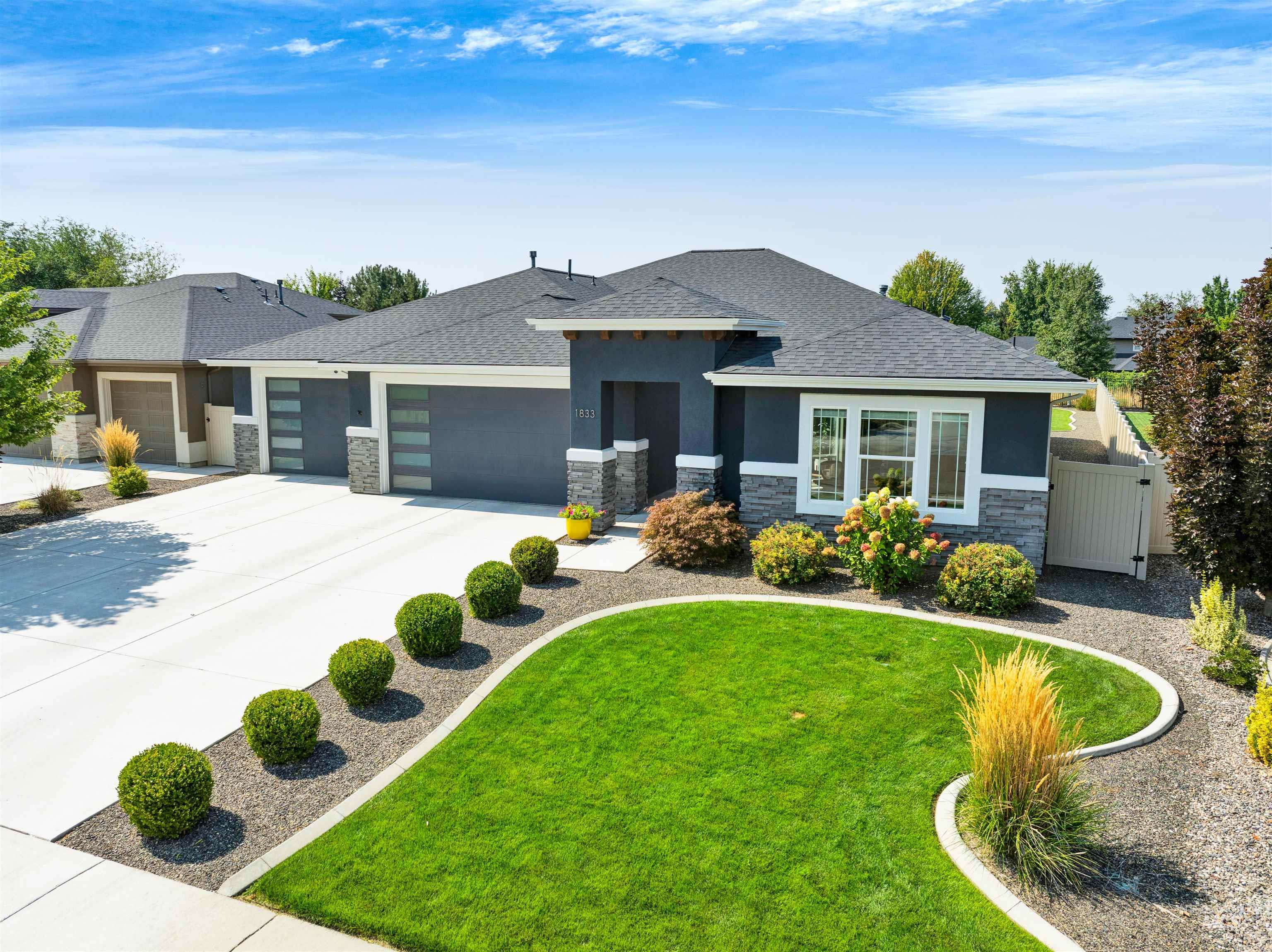 Prairie-style home featuring stone siding, stucco siding, an attached garage, and concrete driveway