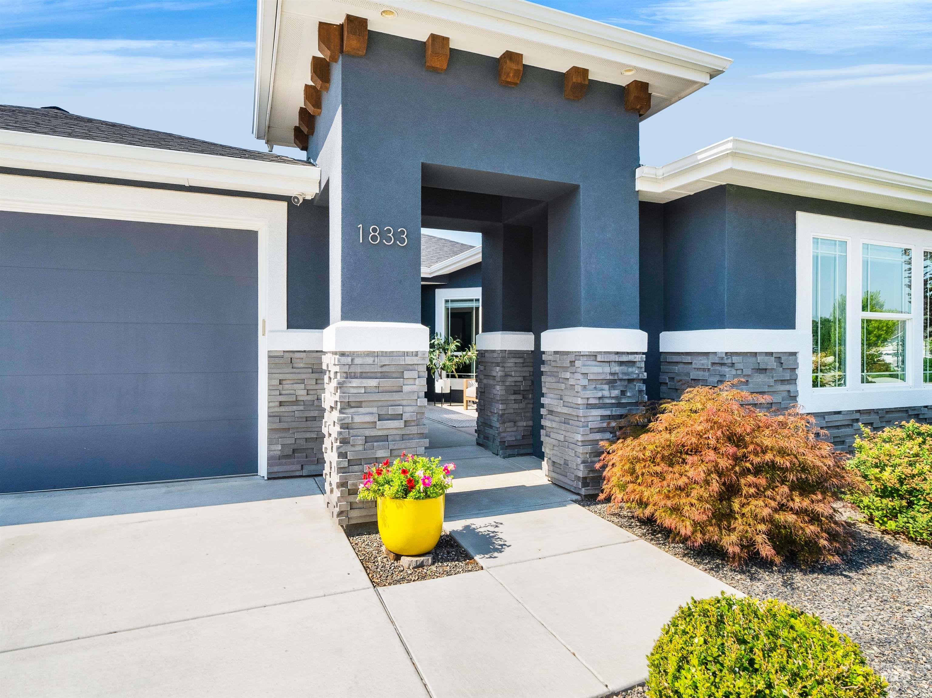 Doorway to property with stone siding, stucco siding, an attached garage, and concrete driveway