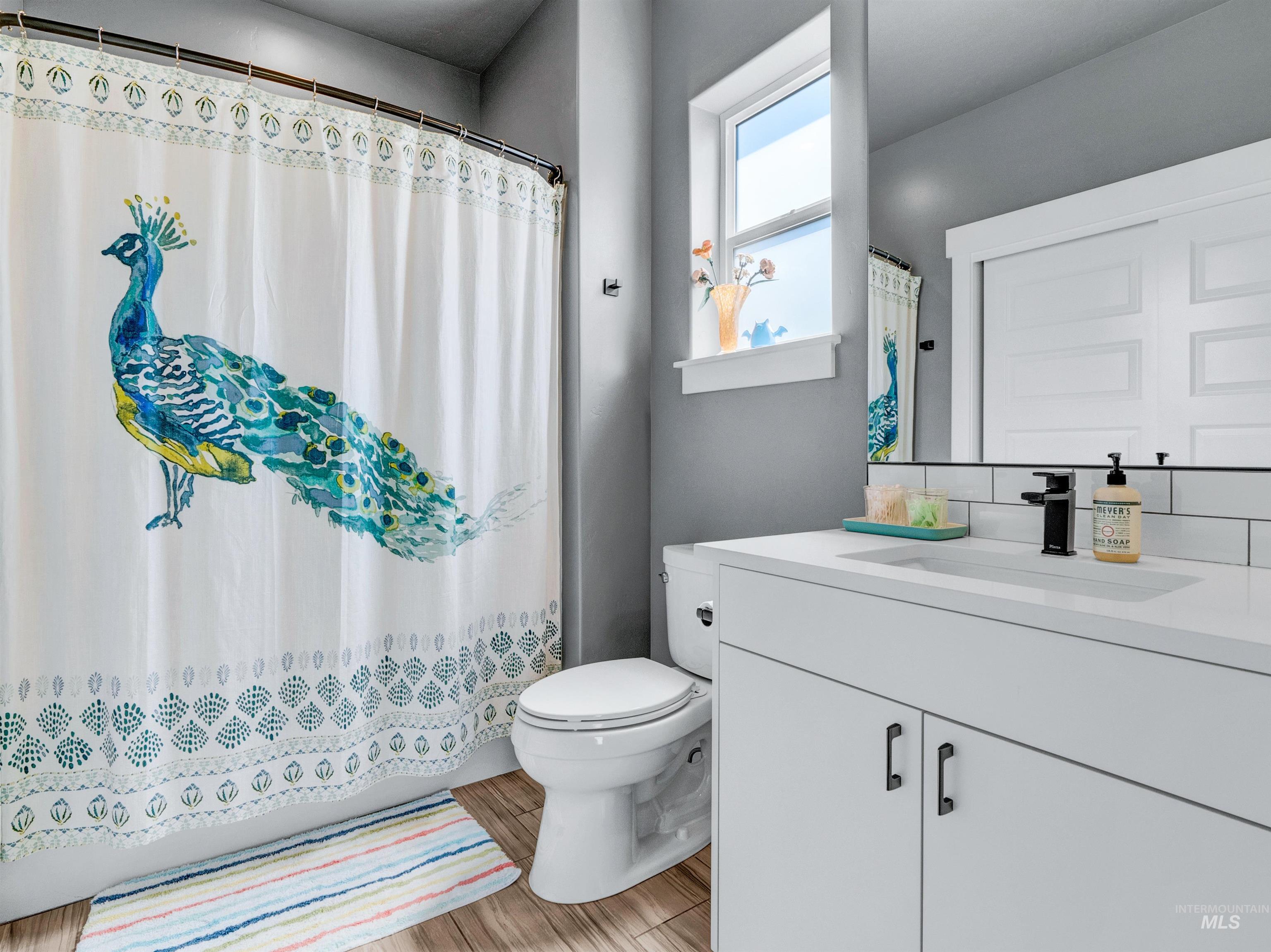 Full bath with vanity, curtained shower, and light wood-type flooring