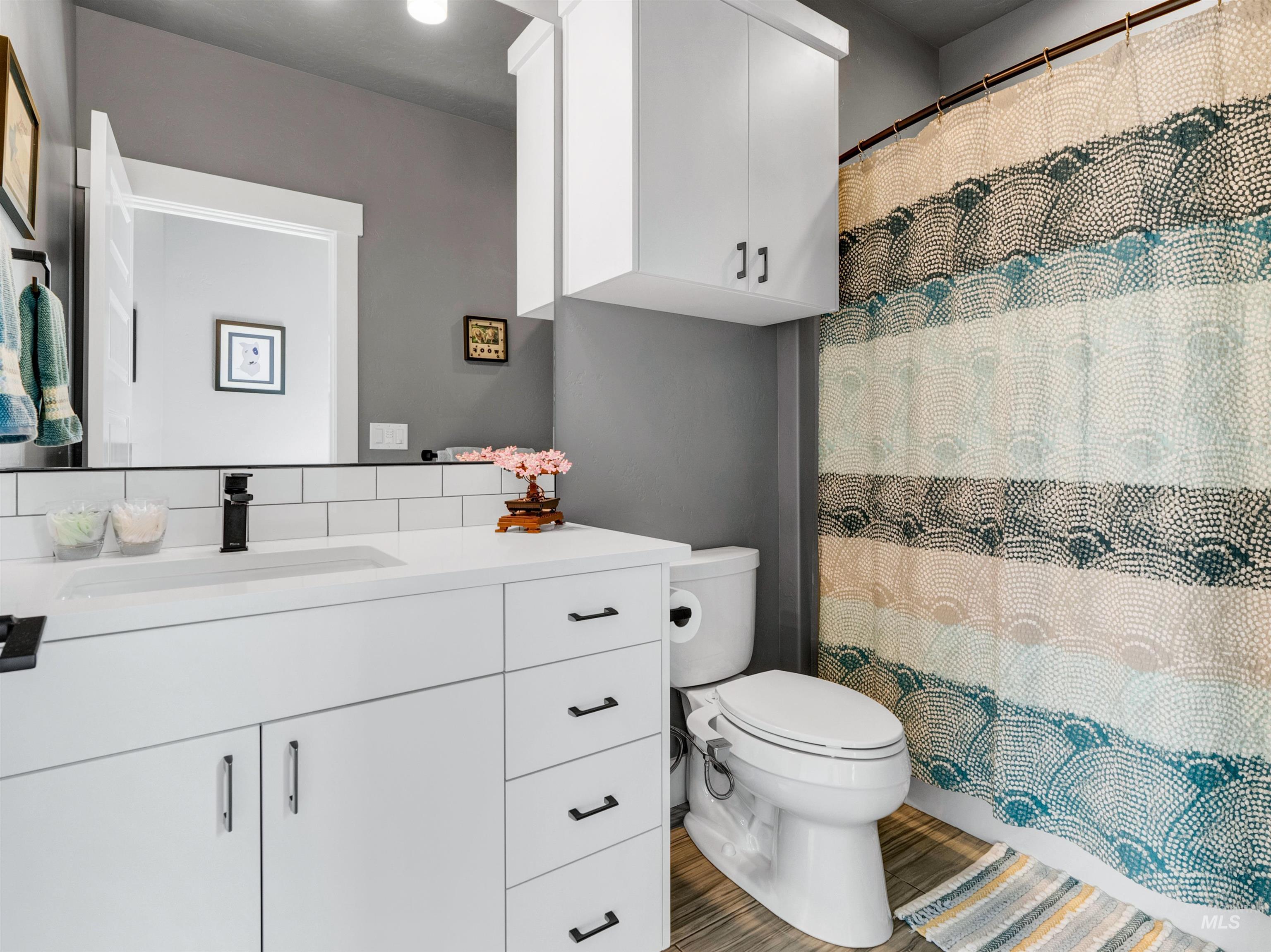 Full bath with vanity, light wood-type flooring, and a shower with curtain