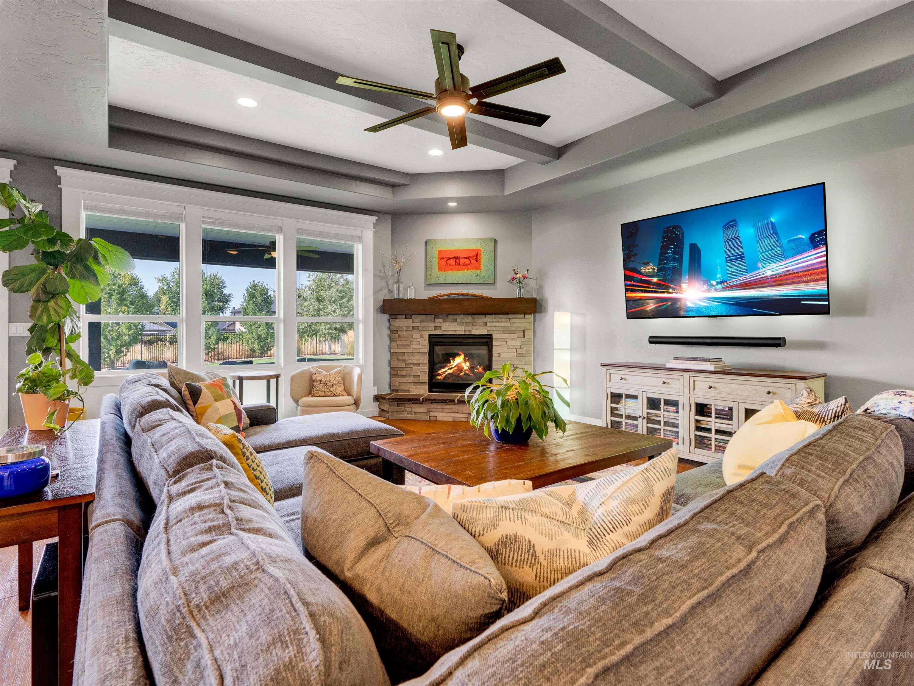 Living area featuring a ceiling fan, beam ceiling, wood finished floors, a fireplace, and recessed lighting