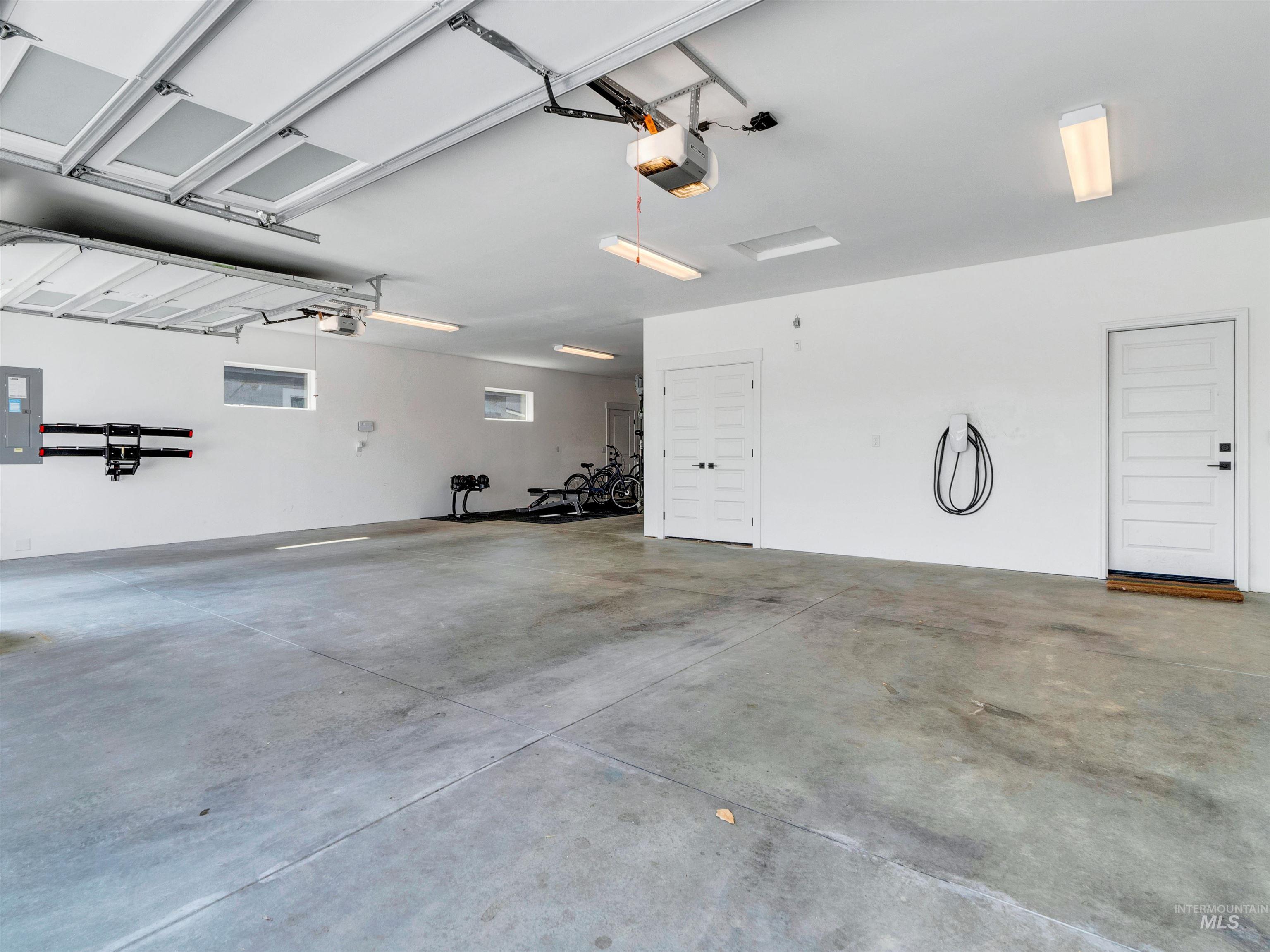 Garage featuring electric panel, a garage door opener, and car charger