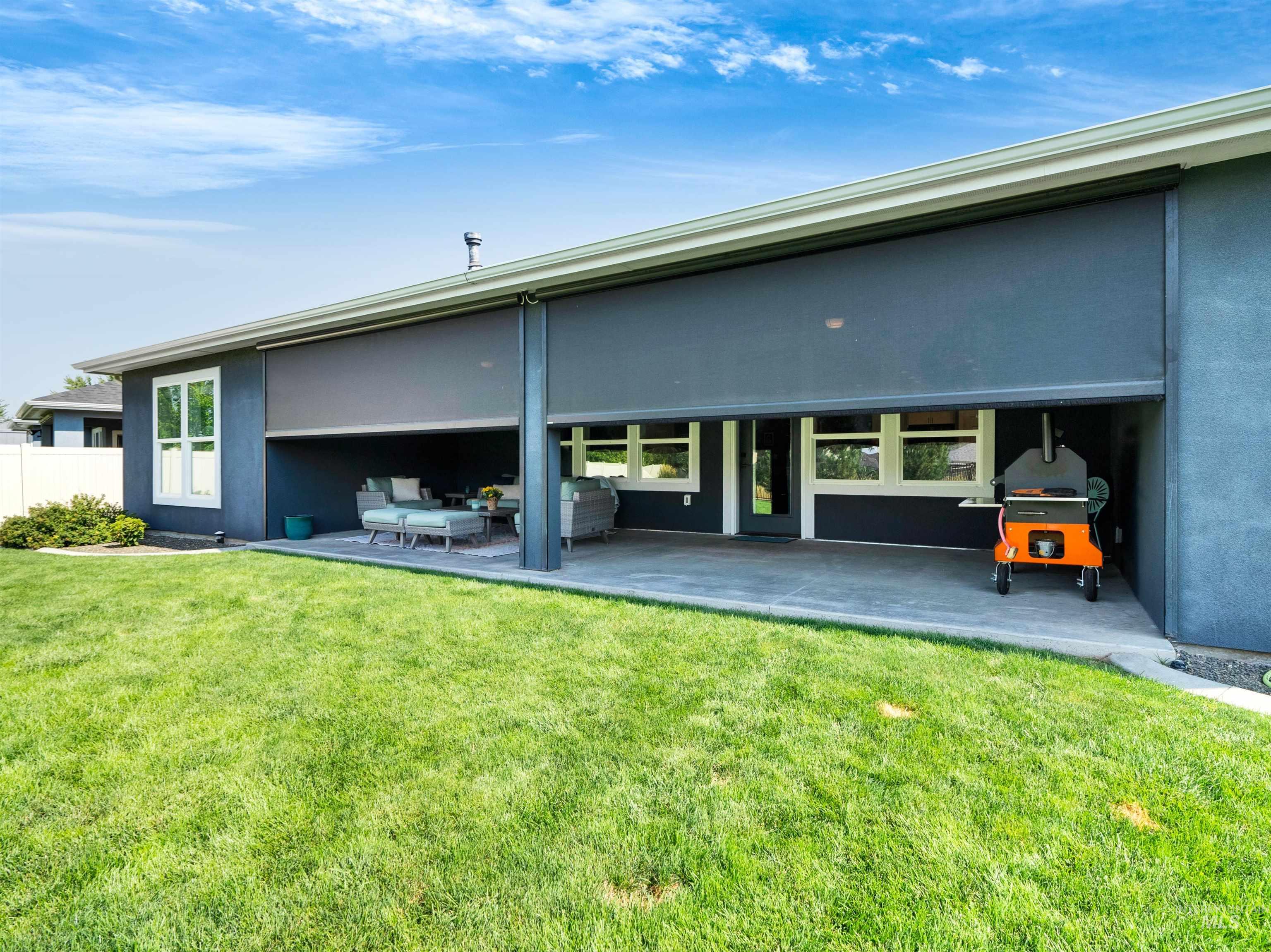 Rear view of property with stucco siding, a patio area, and a yard