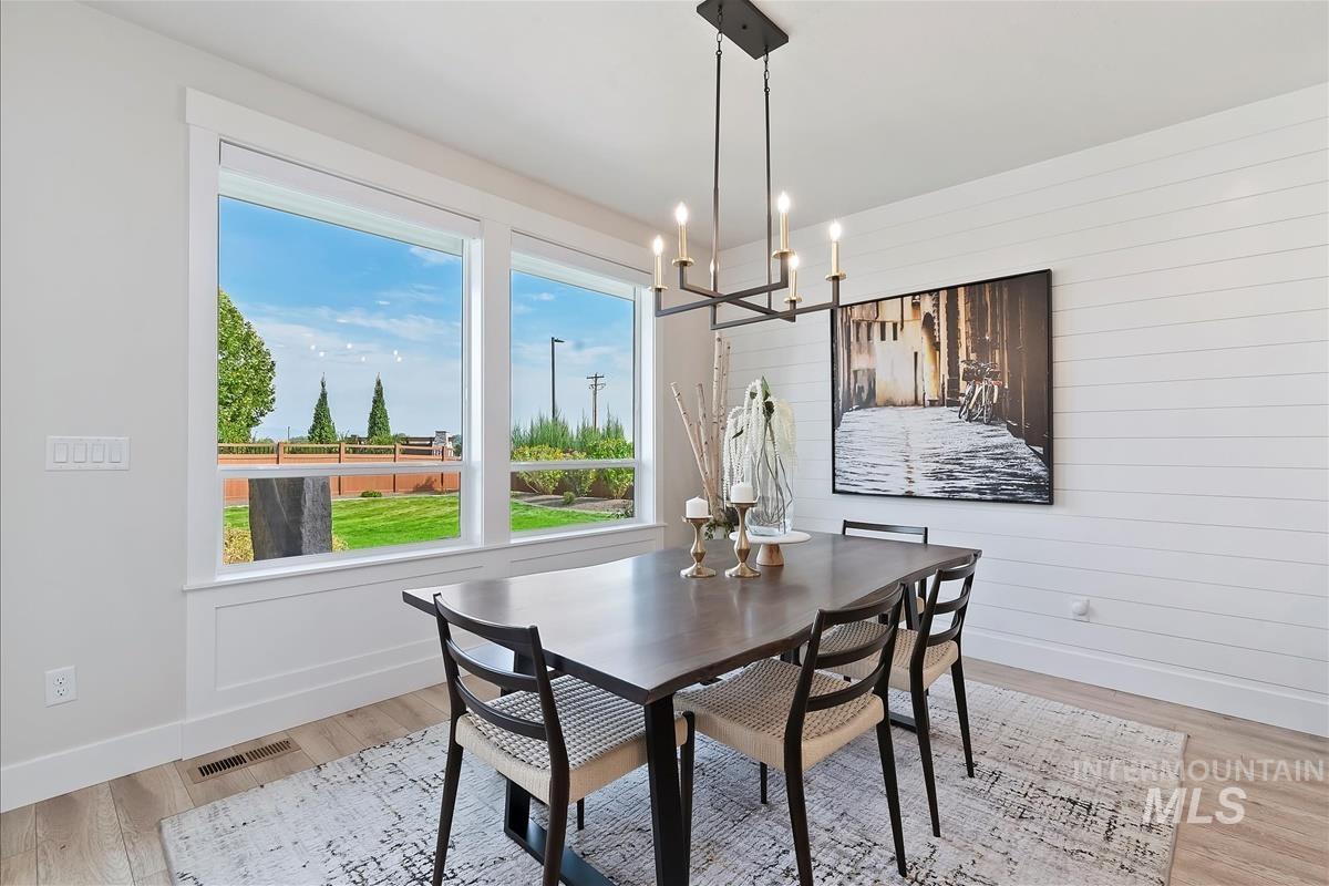 Dining space featuring light wood-type flooring, wood walls, and a chandelier