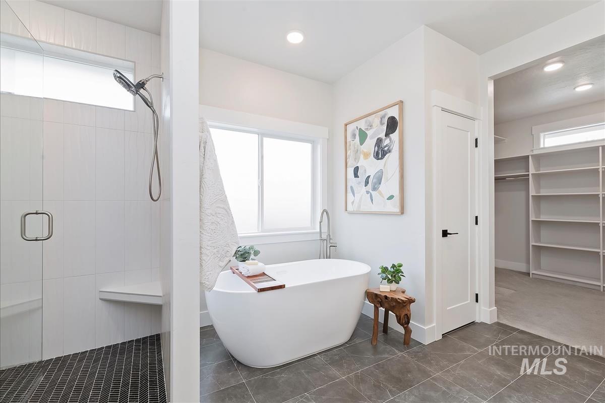 Bathroom featuring a stall shower, a freestanding bath, and a spacious closet