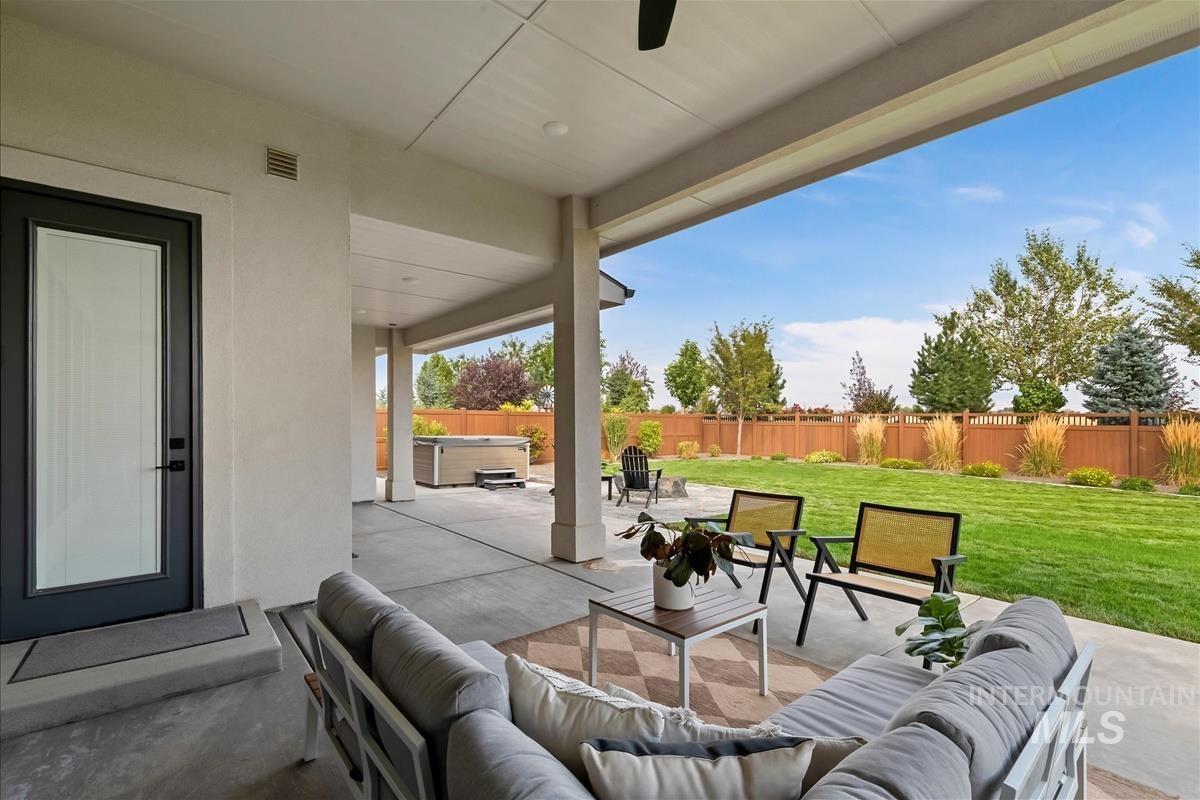 Fenced backyard with outdoor lounge area, a hot tub, a patio, and ceiling fan