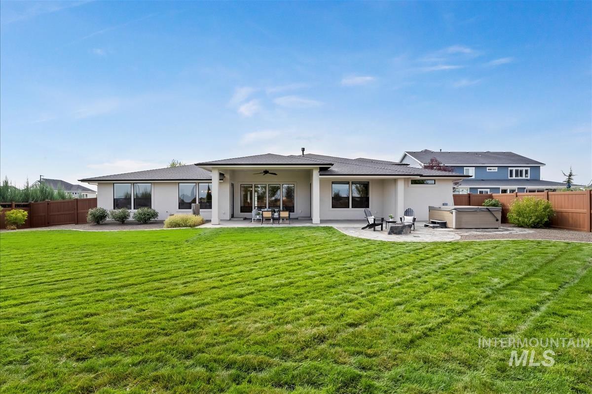 Rear view of house with a hot tub, a ceiling fan, a patio, and a fenced backyard