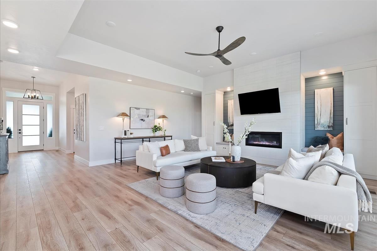 Living area featuring light wood-type flooring, a large fireplace, recessed lighting, and a ceiling fan