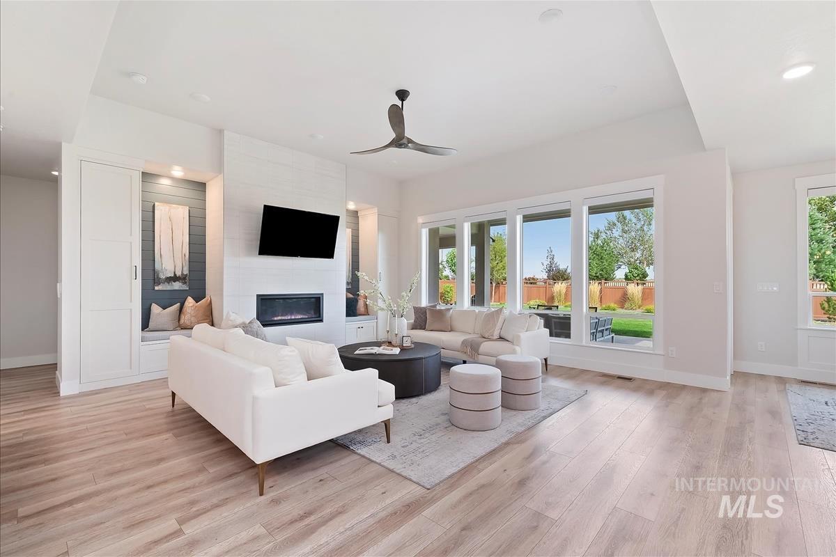 Living area featuring healthy amount of natural light, recessed lighting, a large fireplace, ceiling fan, and light wood-style flooring