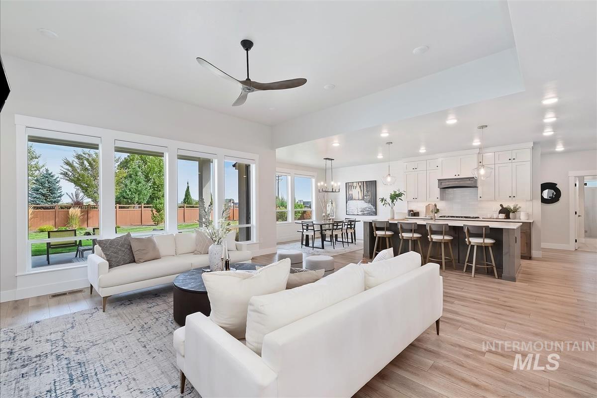 Living room featuring ceiling fan, light wood finished floors, a chandelier, and recessed lighting
