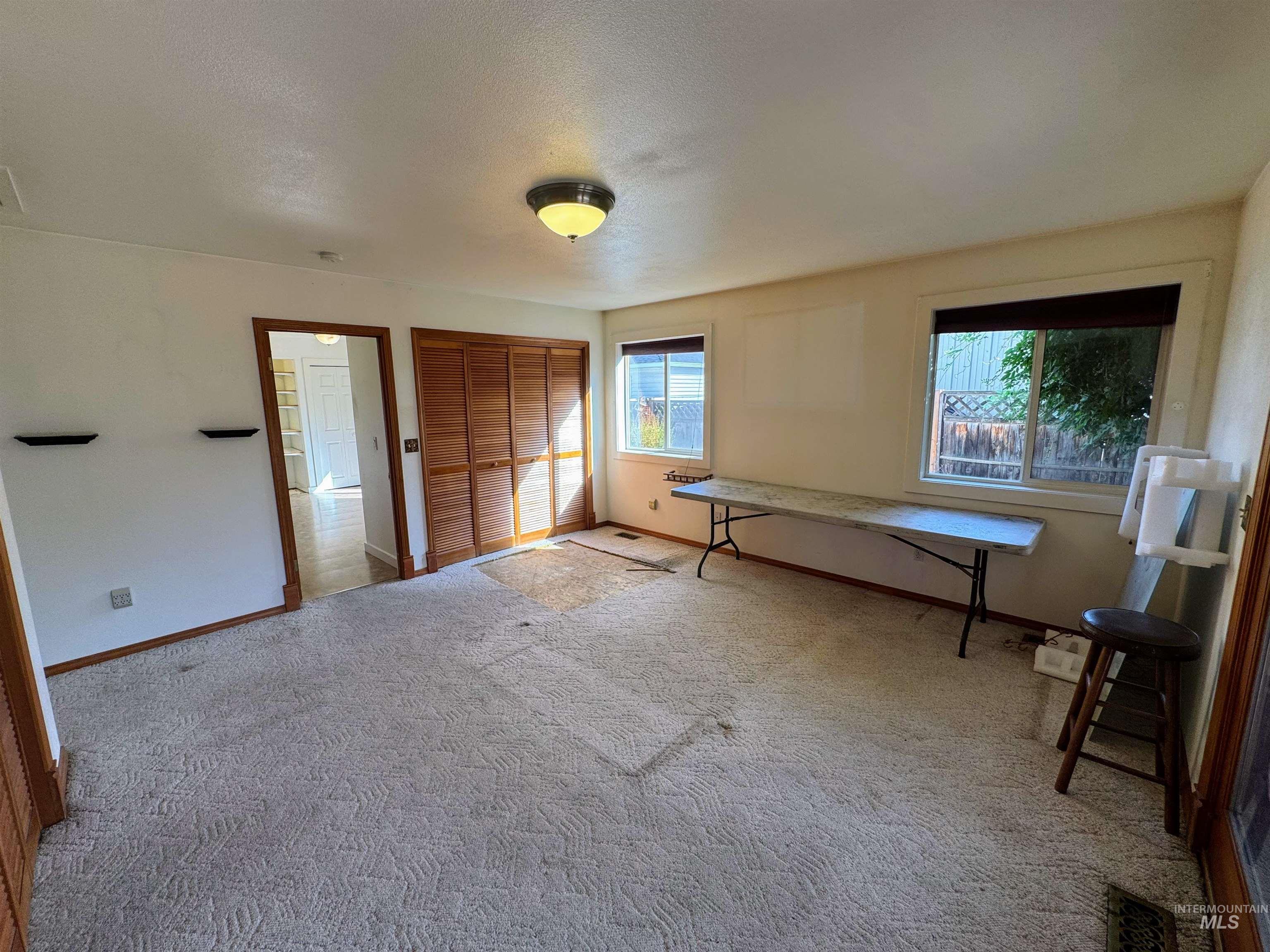 Unfurnished bedroom with multiple windows, a closet, carpet floors, and a textured ceiling