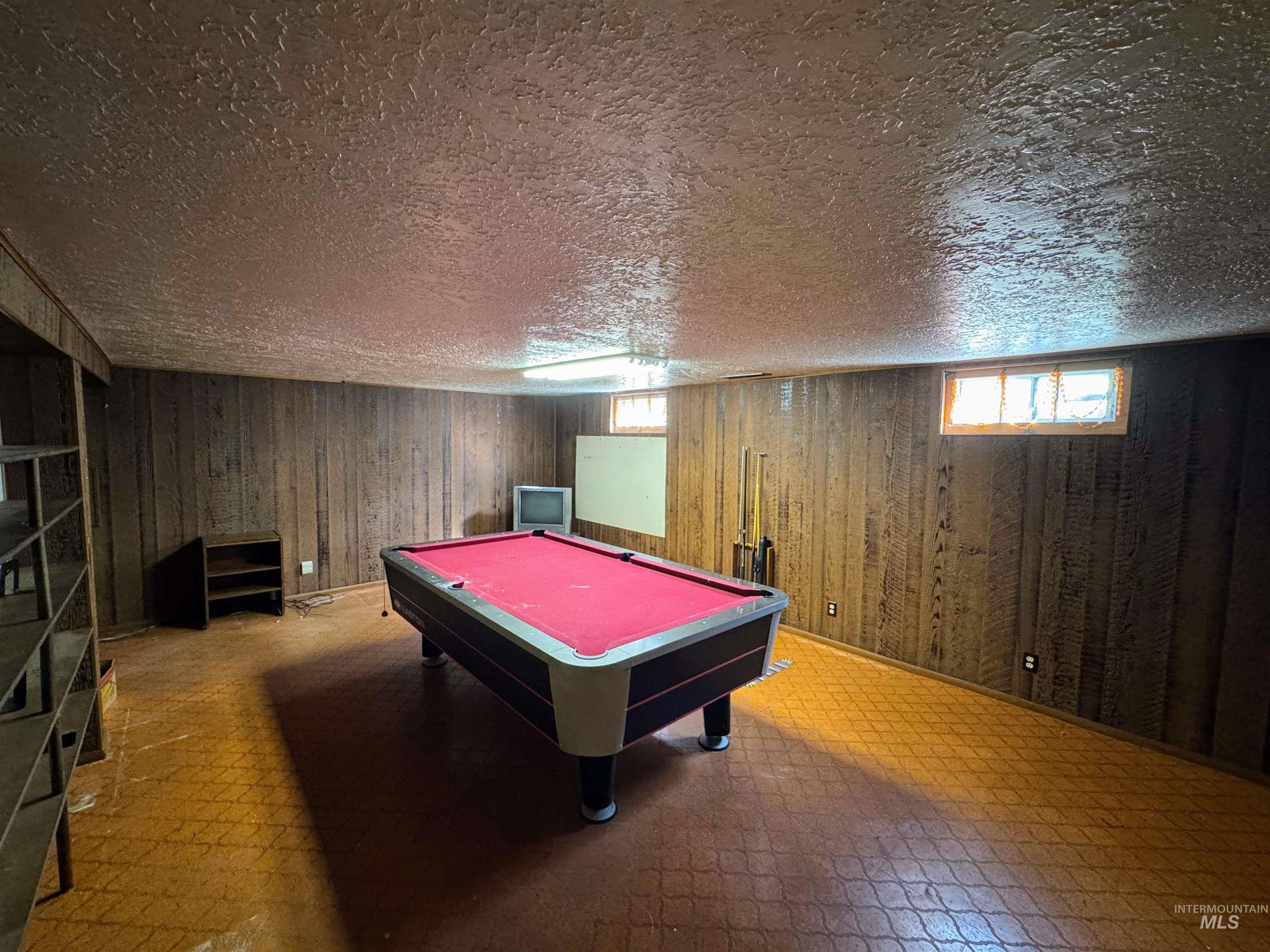 Playroom featuring billiards table, wooden walls, tile patterned floors, and a textured ceiling